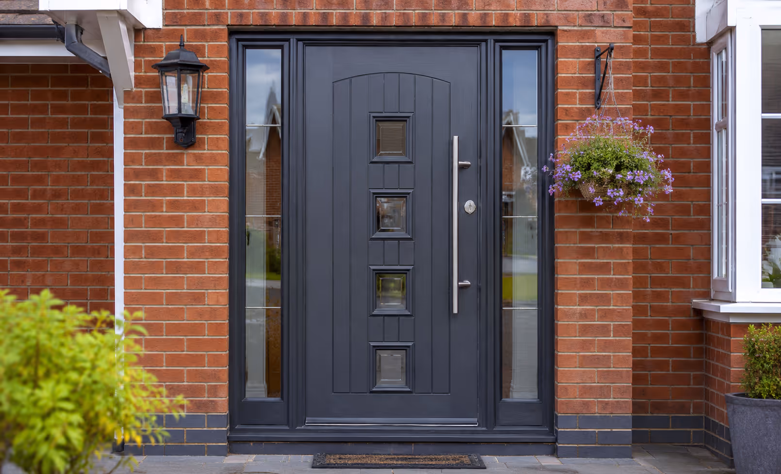 Anthracite grey composite front door with glass side panels fitted on a brick house