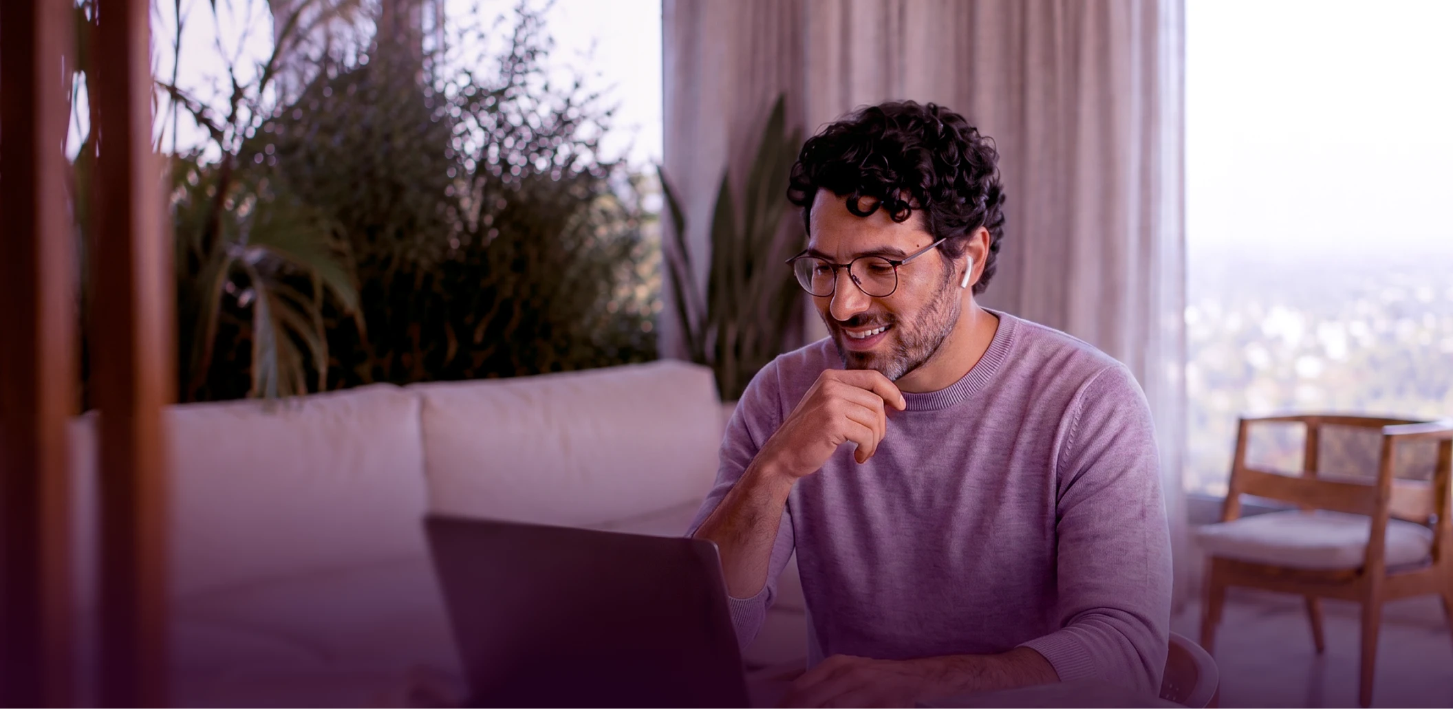 Homem de óculos usando um notebook em uma sala.