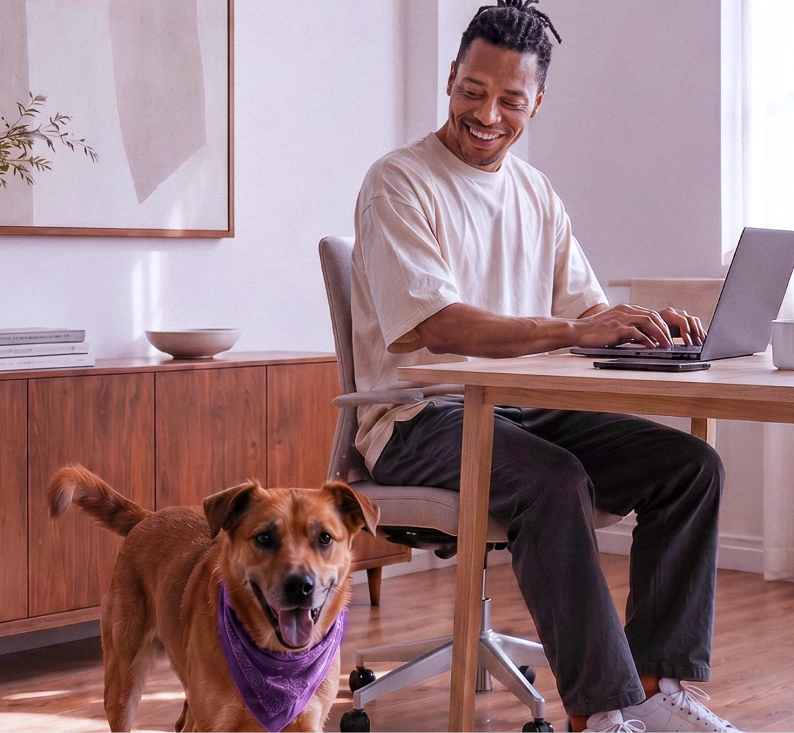Homem sorridente usando um notebook em uma mesa de trabalho.