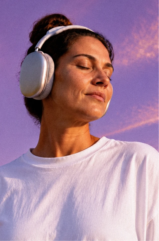 Mulher usando fones de ouvido com os olhos fechados.