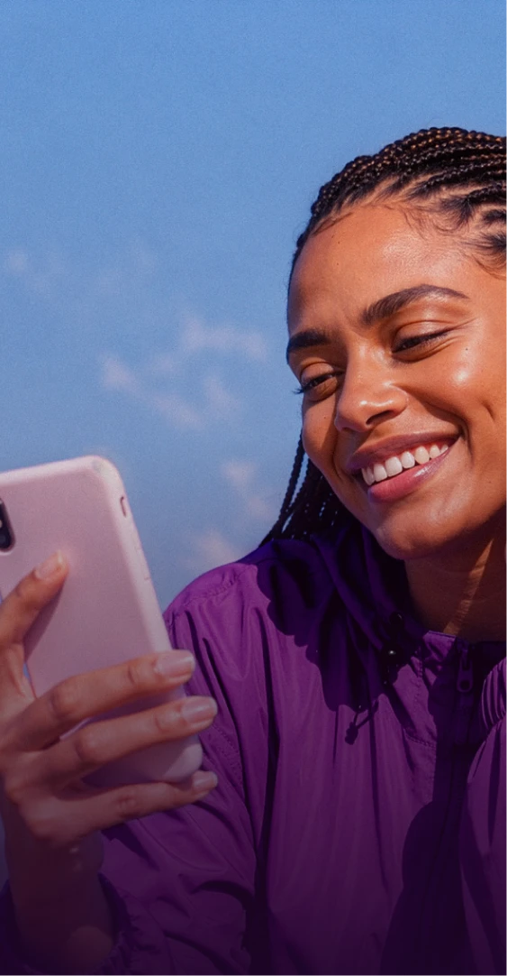 Mulher sorridente olhando para um celular.