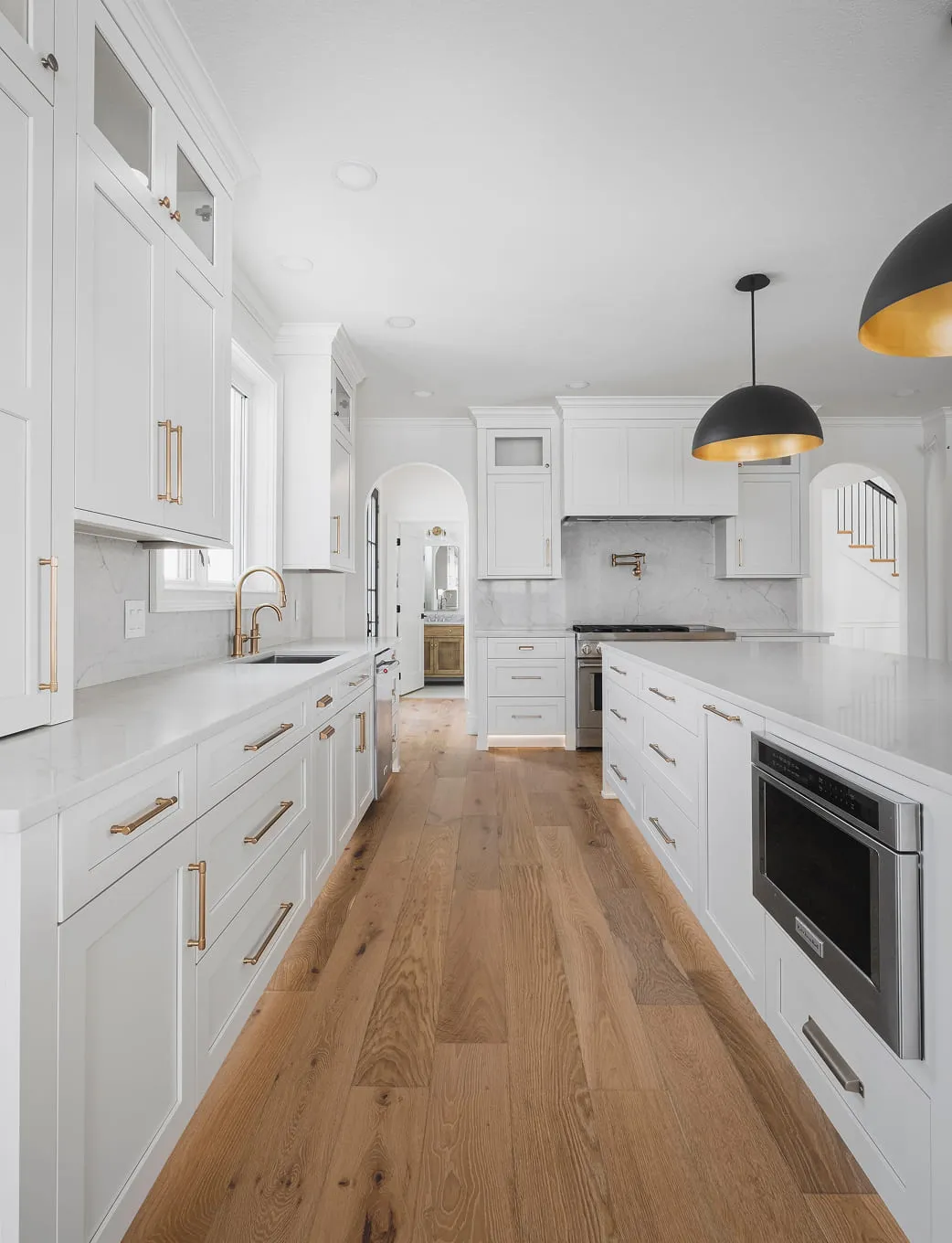 A kitchen with white cabinets and wood floors.