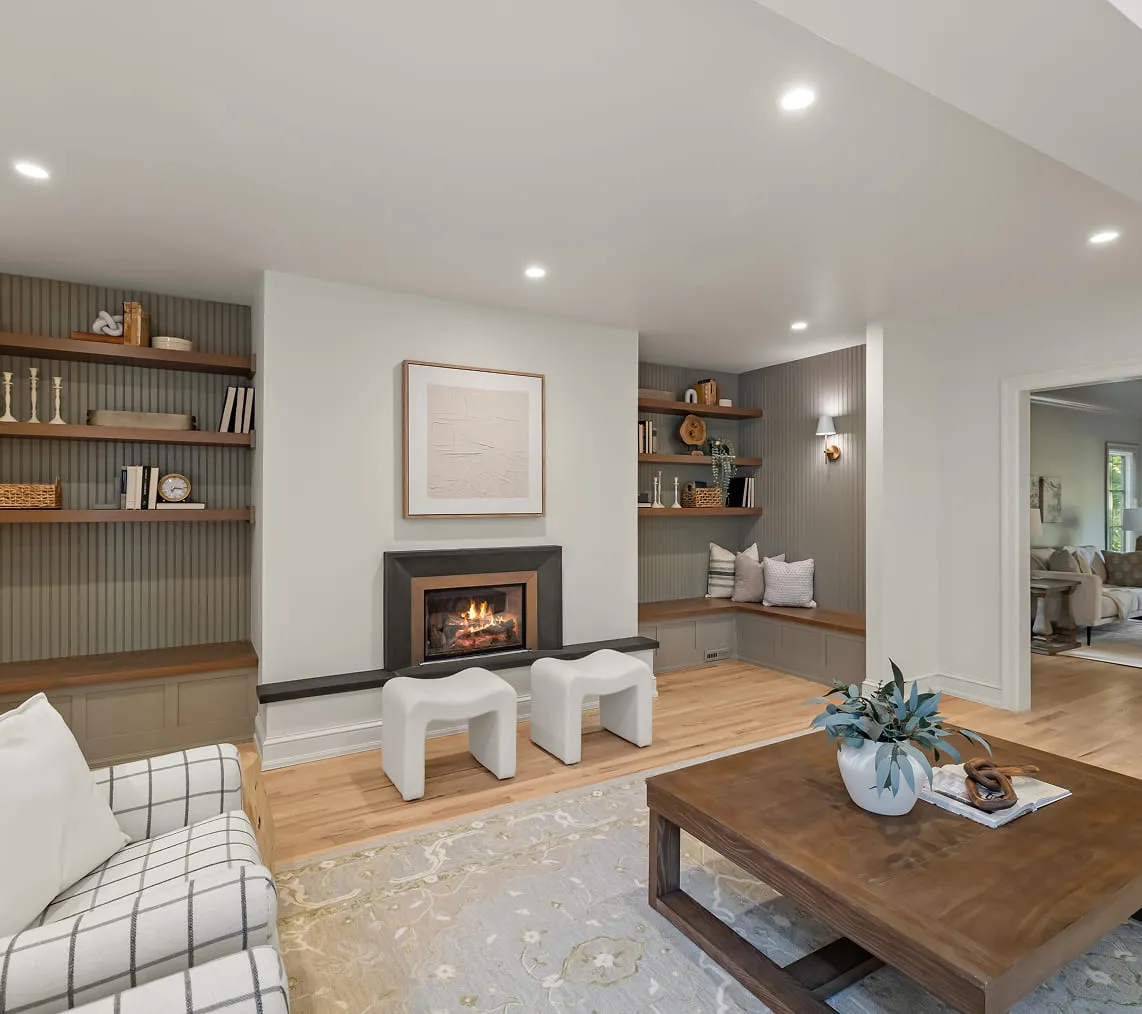 Modern living room with a fireplace, built-in shelves, white stools, a coffee table, and a gray sofa.