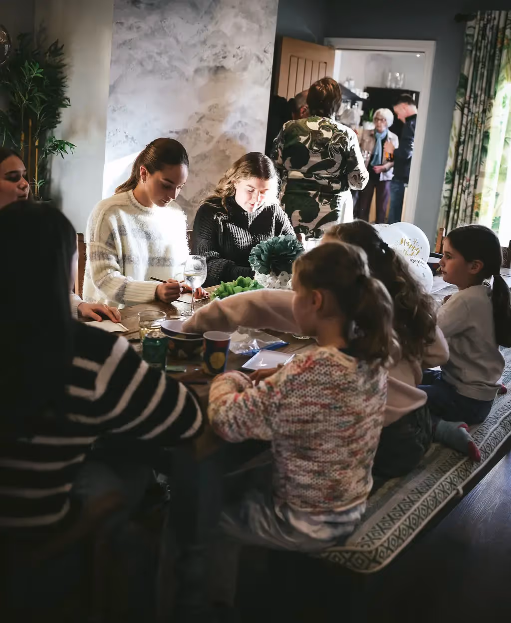 Family of adults and children doing crafts together around a dining table