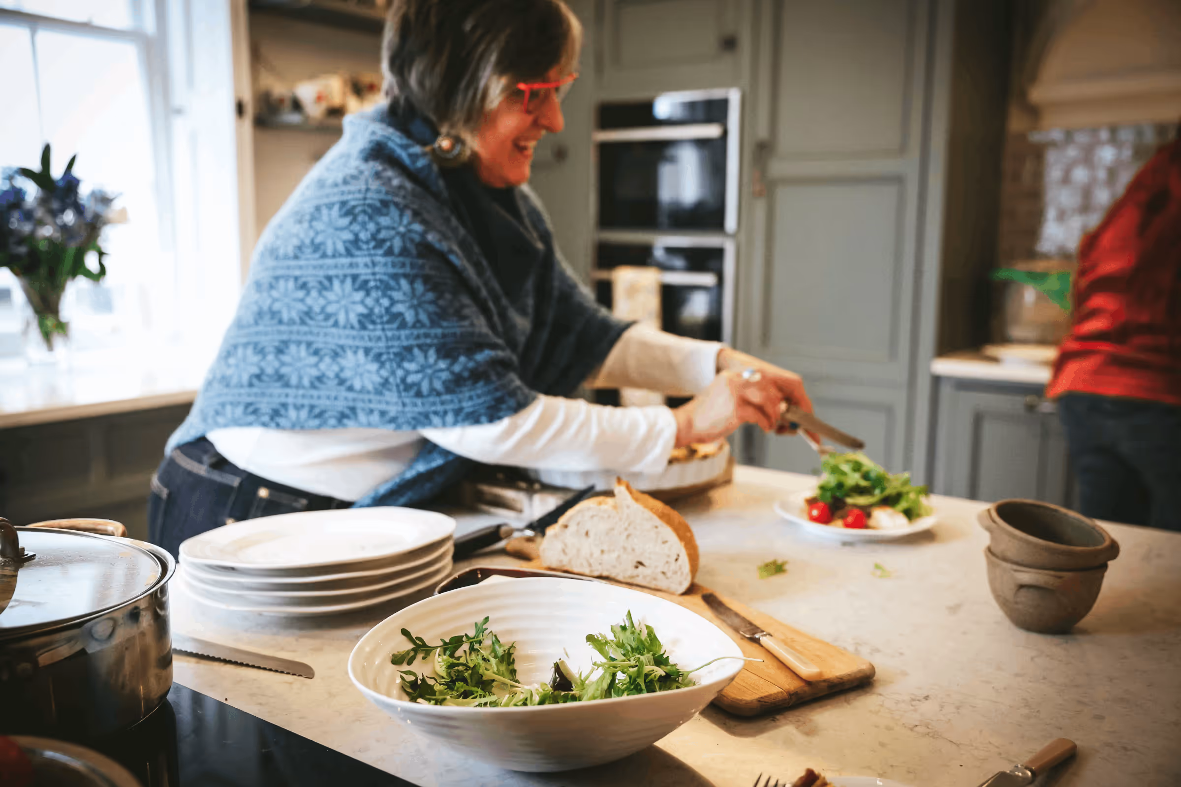 Woman serving fresh salad and bread in a country kitchen