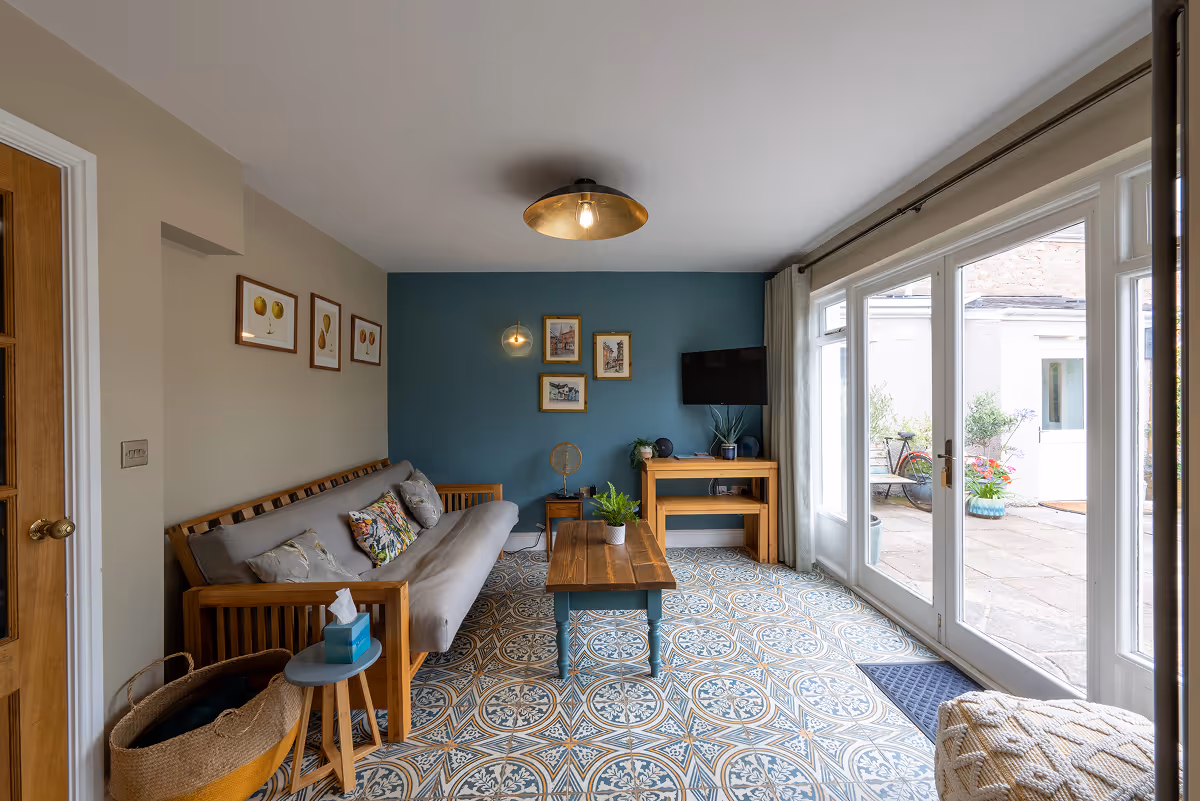 Bright living room with patterned tiled floor and patio doors to courtyard