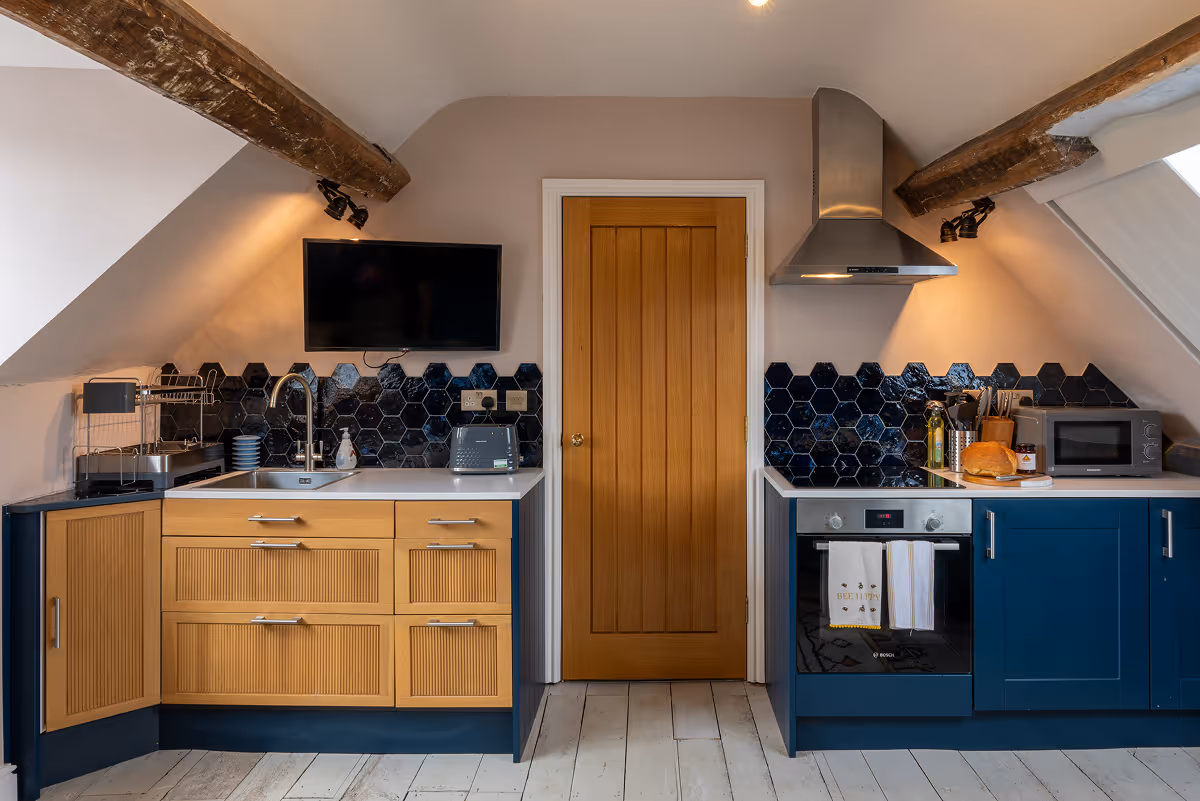 Modern kitchen with navy and oak cabinets, exposed beams and sloped ceiling