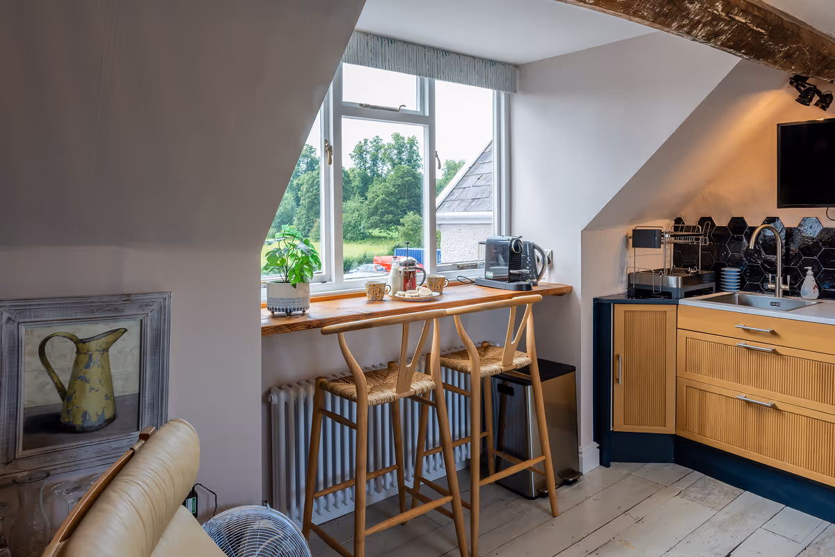 Kitchen breakfast bar with stools beneath a window overlooking greenery