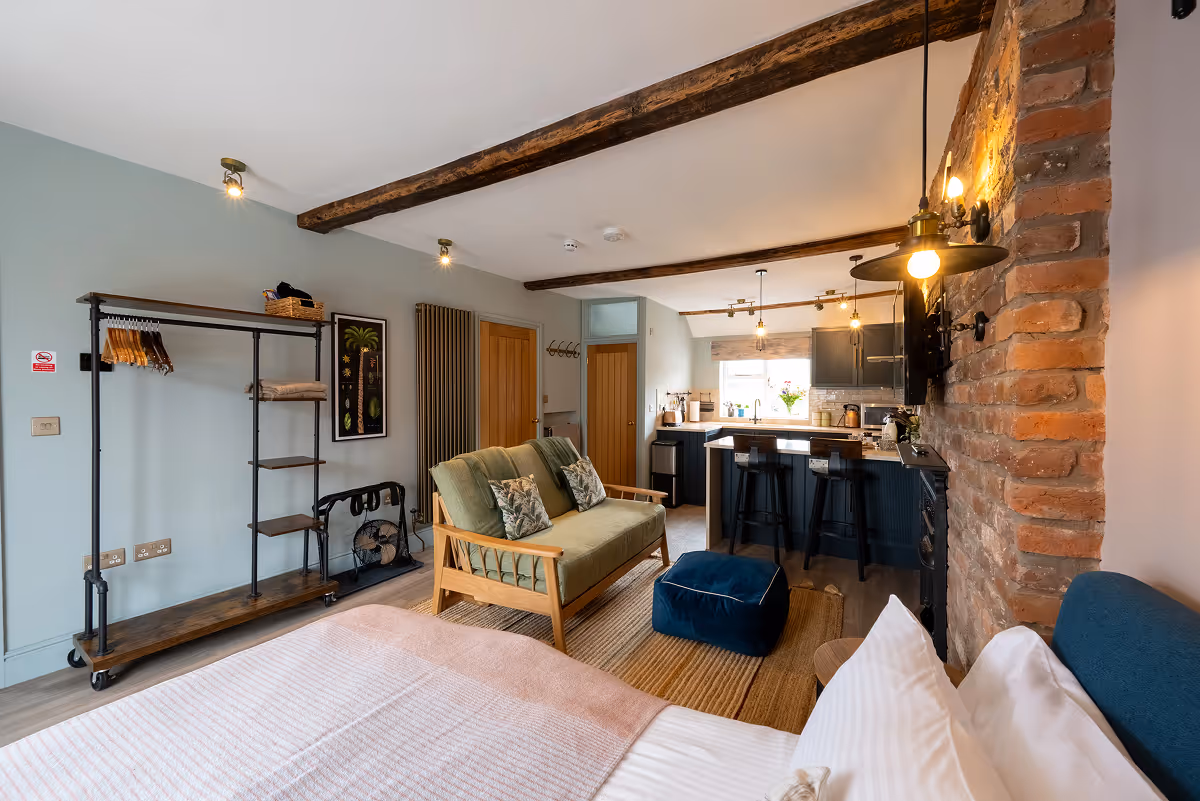 Open-plan studio with bed, sofa, exposed beams and modern kitchen
