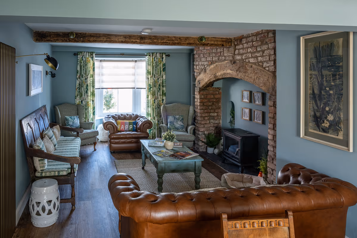 Cosy living room with leather chesterfield sofa, exposed brick fireplace and armchairs
