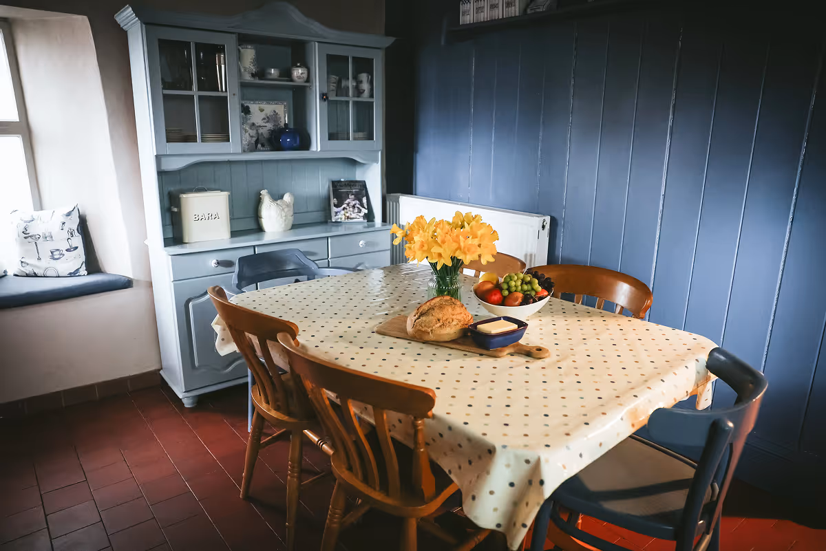 Country kitchen with dresser, tiled floor and flowers on table