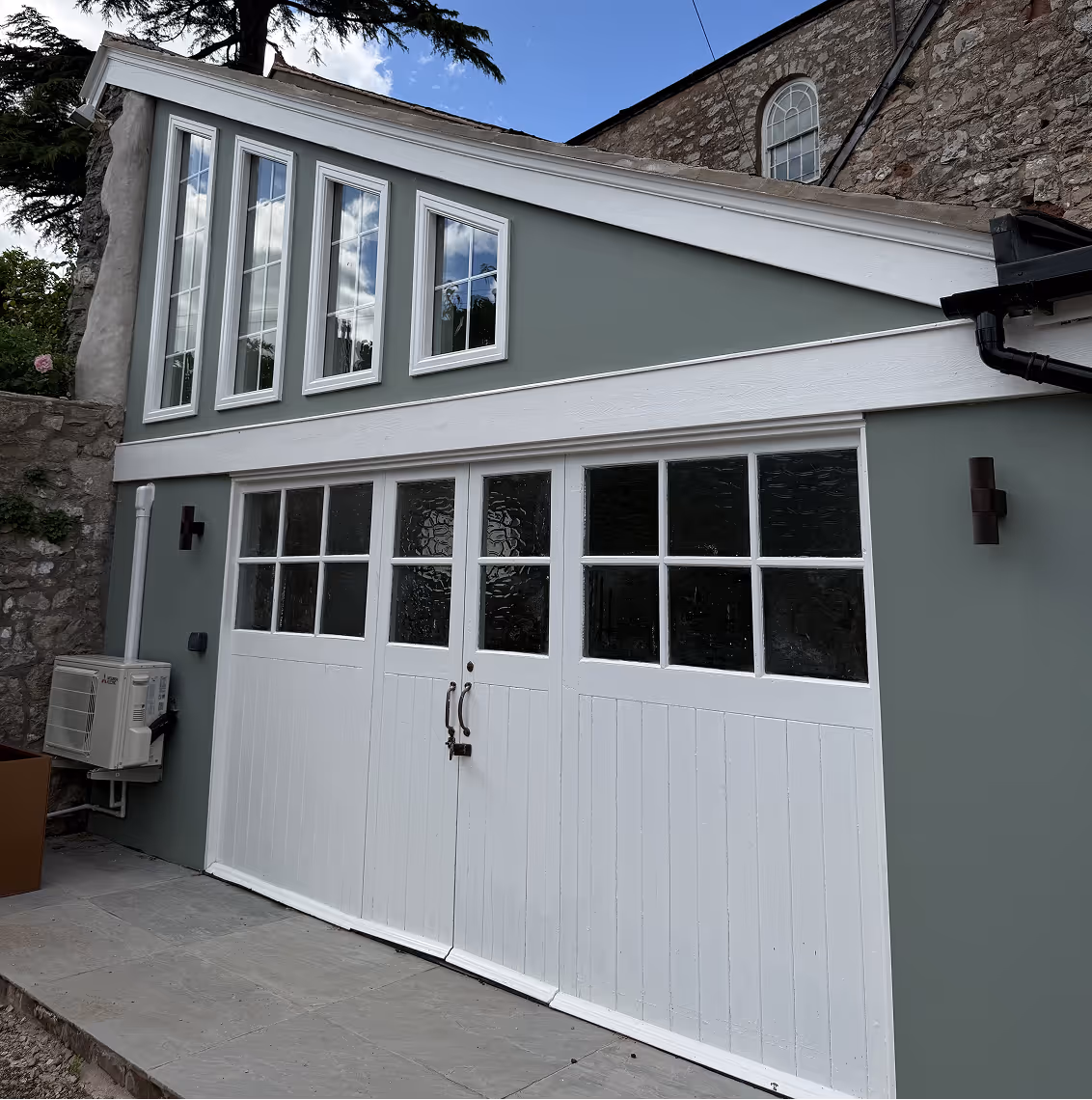 Renovated garage with sage green walls and white folding garage doors