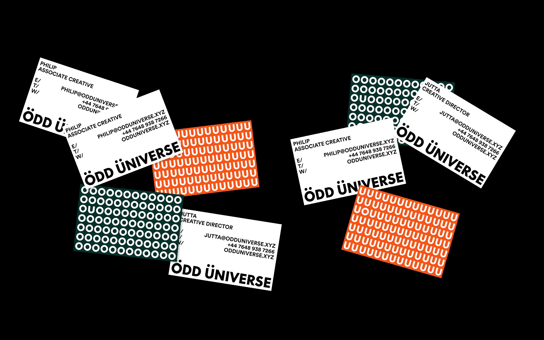 Odd Universe business cards in black, white and orange scattered across a dark surface