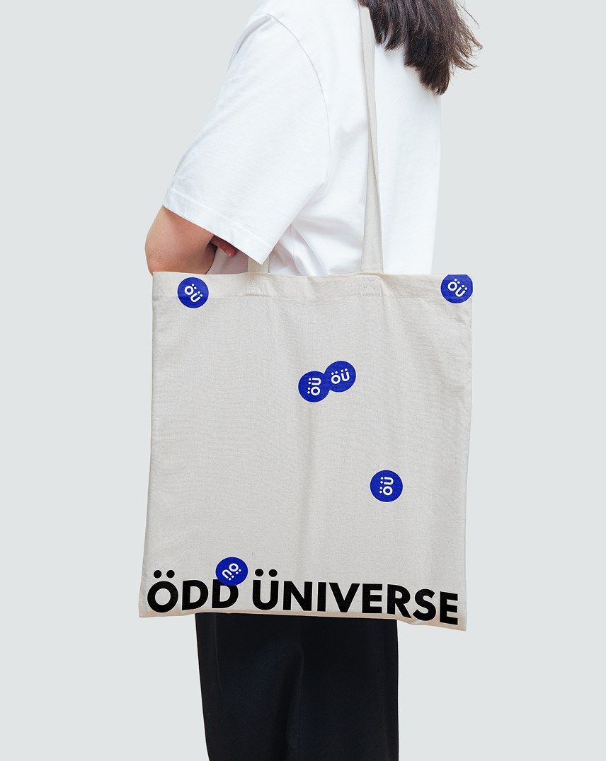 Odd Universe white tote bag with a blue dot pattern and ou logo, held by a person
