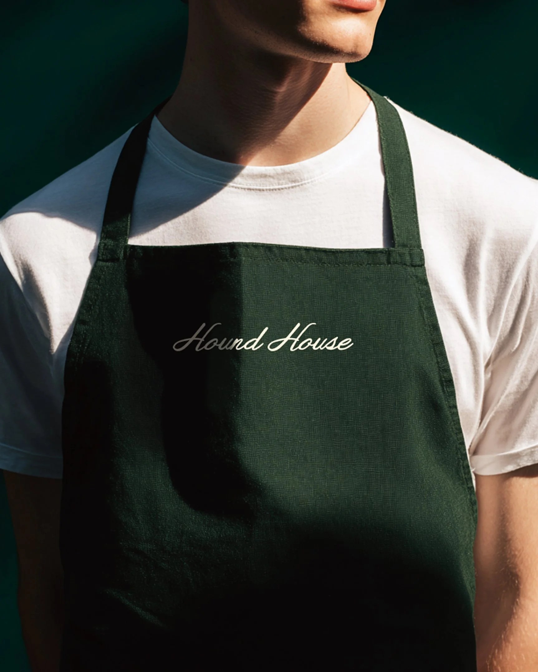 Hound House dark green staff apron mockup with the embroidered logo