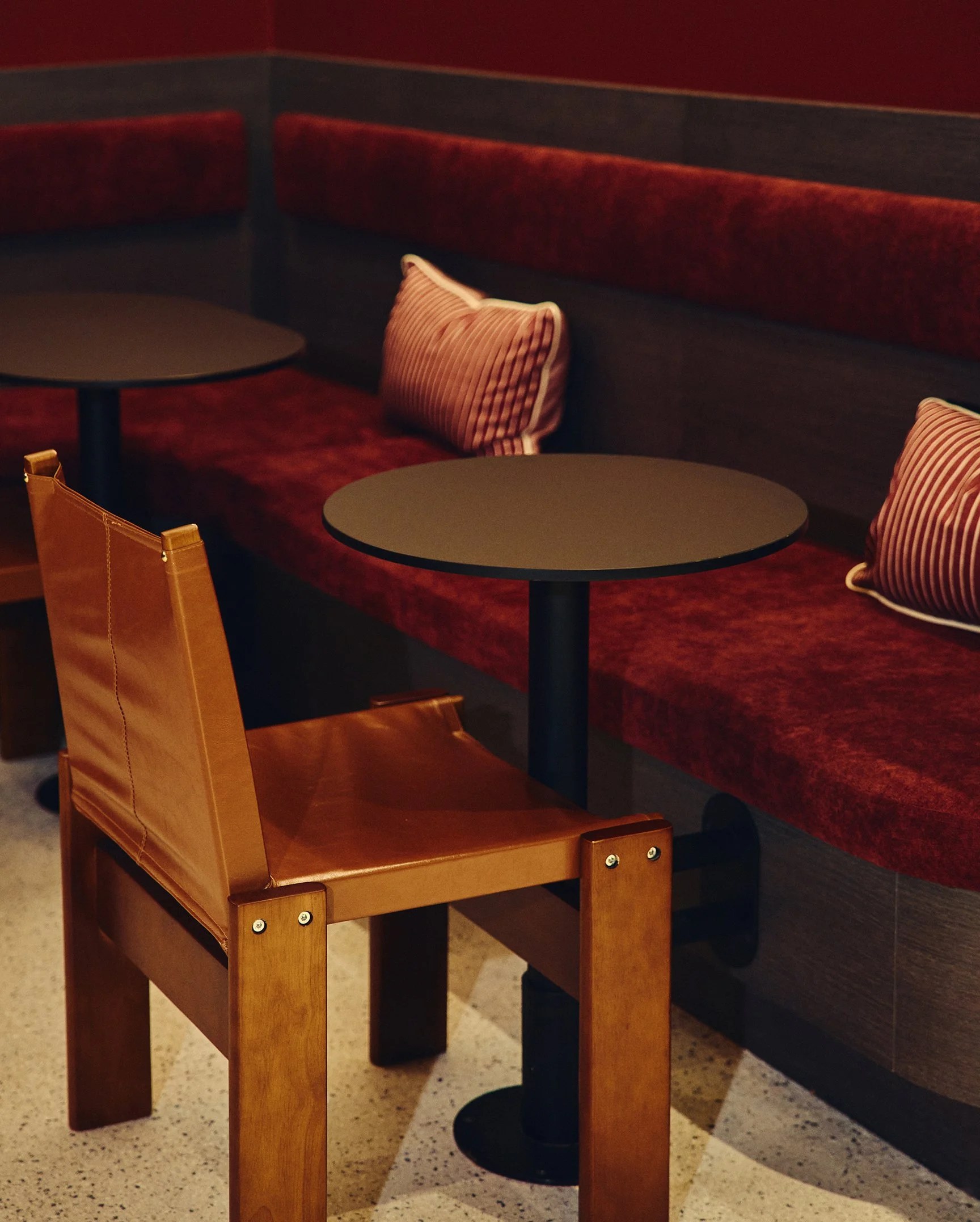 Hound House interior — a red banquette and wooden chair in the cafe space
