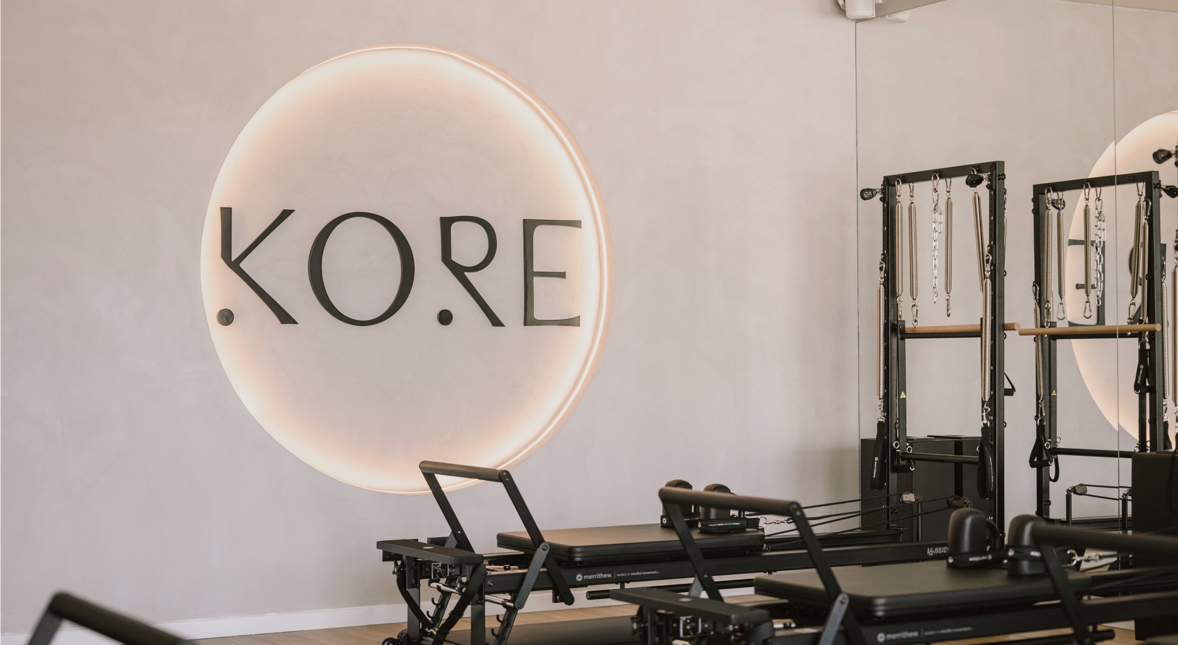Kore Pilates circular wall logo lit up inside the reformer studio