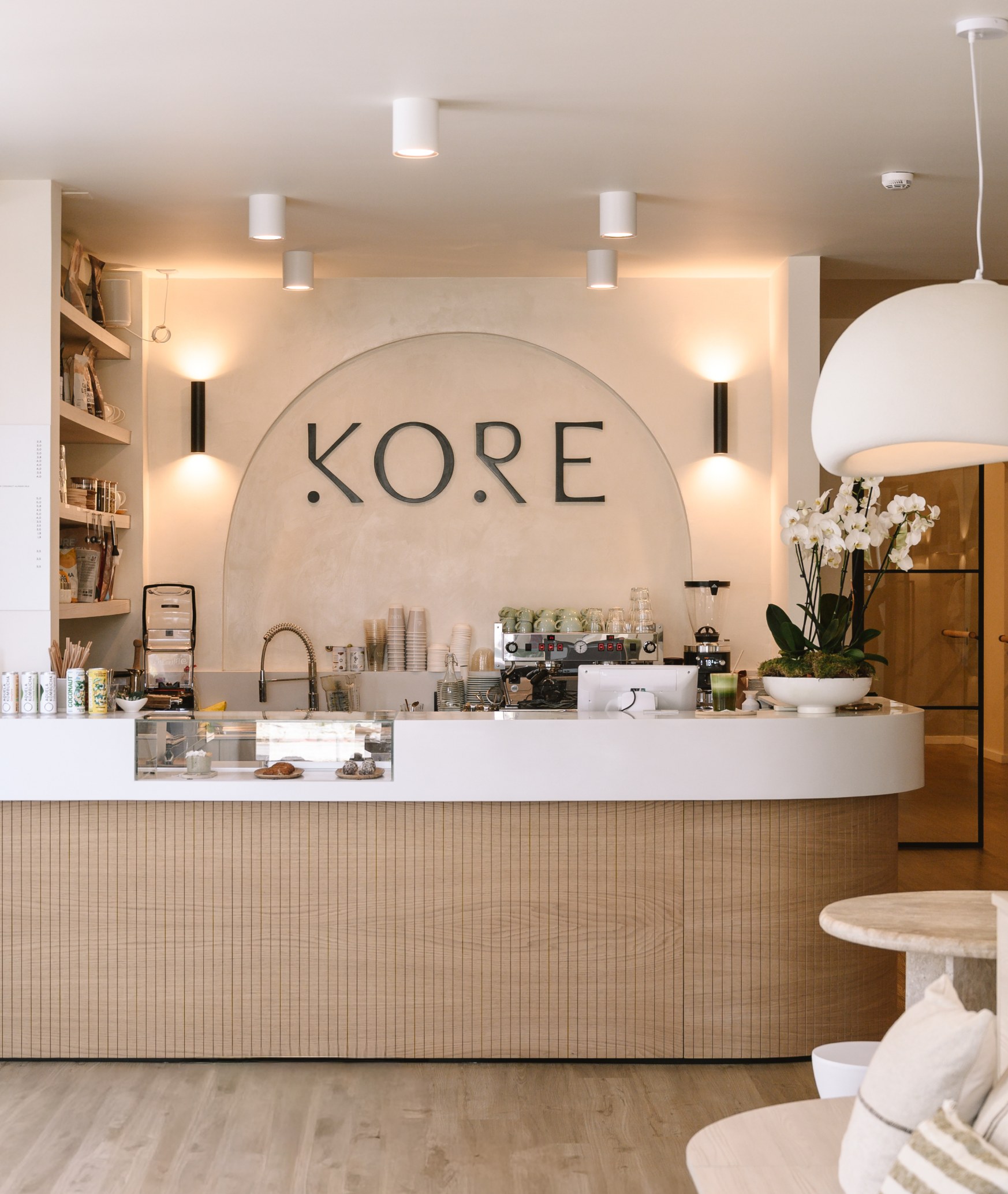 Kore Pilates café interior with the illuminated wall logo above the counter