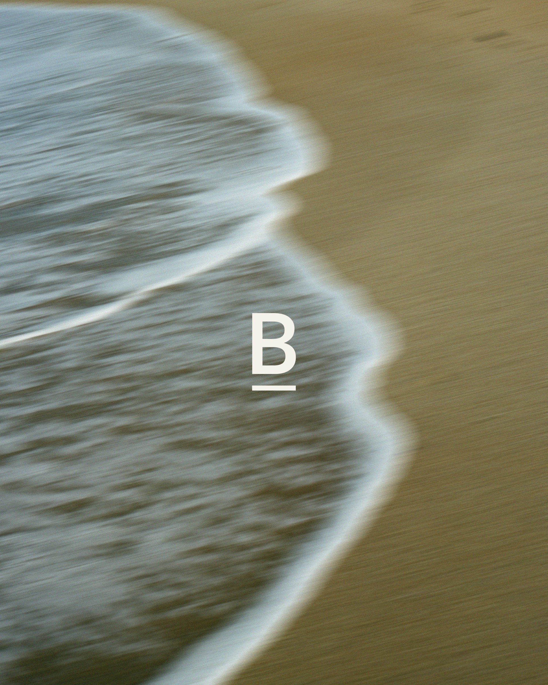Baseline B monogram over a blurred sandy shoreline