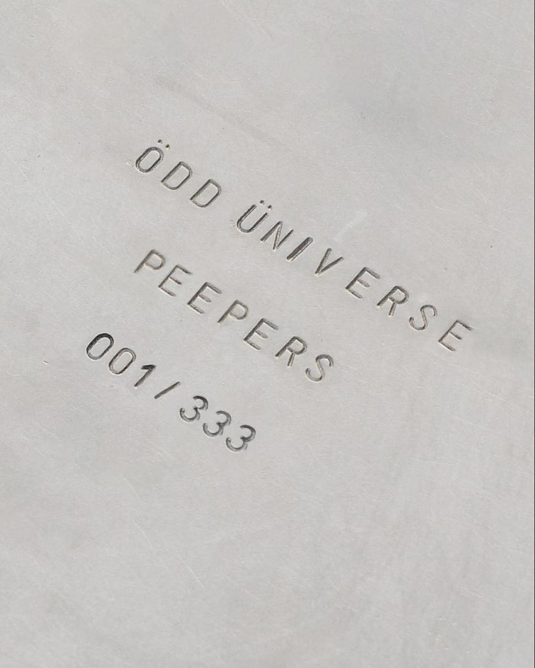 Odd Universe Peepers wordmark embossed on a stone surface
