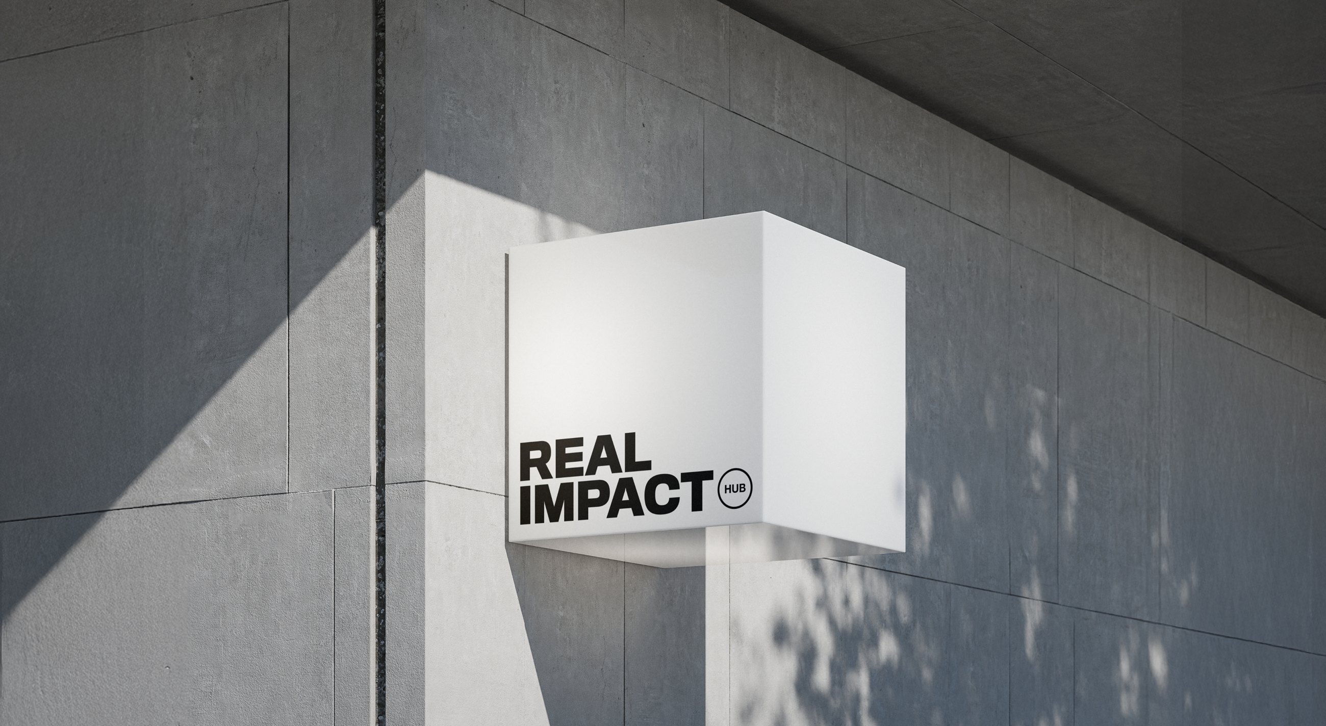 Real Impact Hub illuminated sign mounted on a concrete building exterior