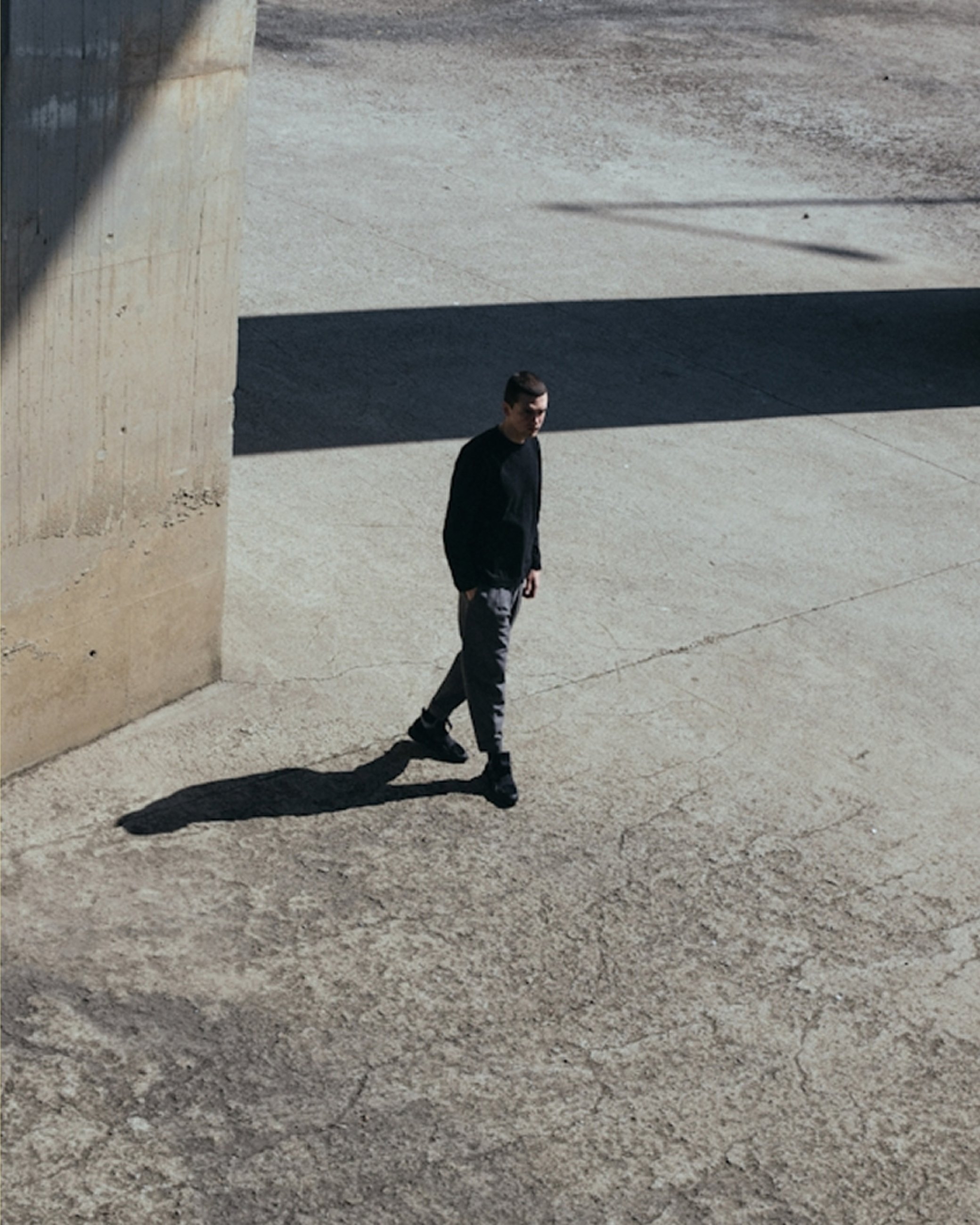 Person walking through a brutalist concrete space with a long shadow for Real Impact Hub