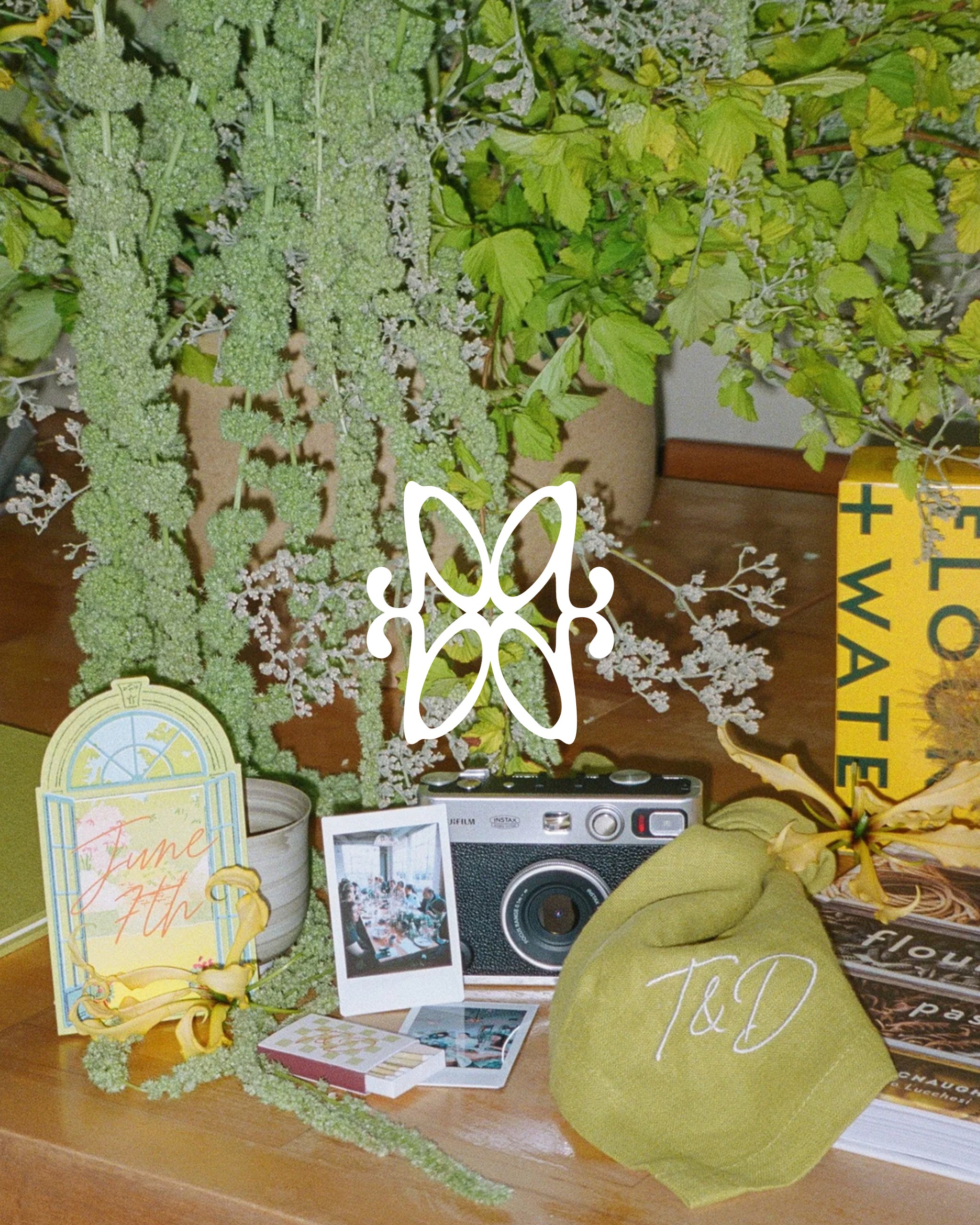 Atelier Amarise wedding welcome table — trailing greenery, Instax camera, June 7th card and monogrammed T&D favour