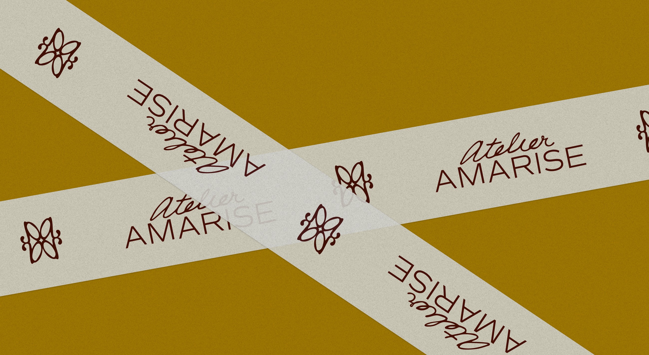 Atelier Amarise branded packing tape criss-crossed on an ochre background with script logo and floral icon