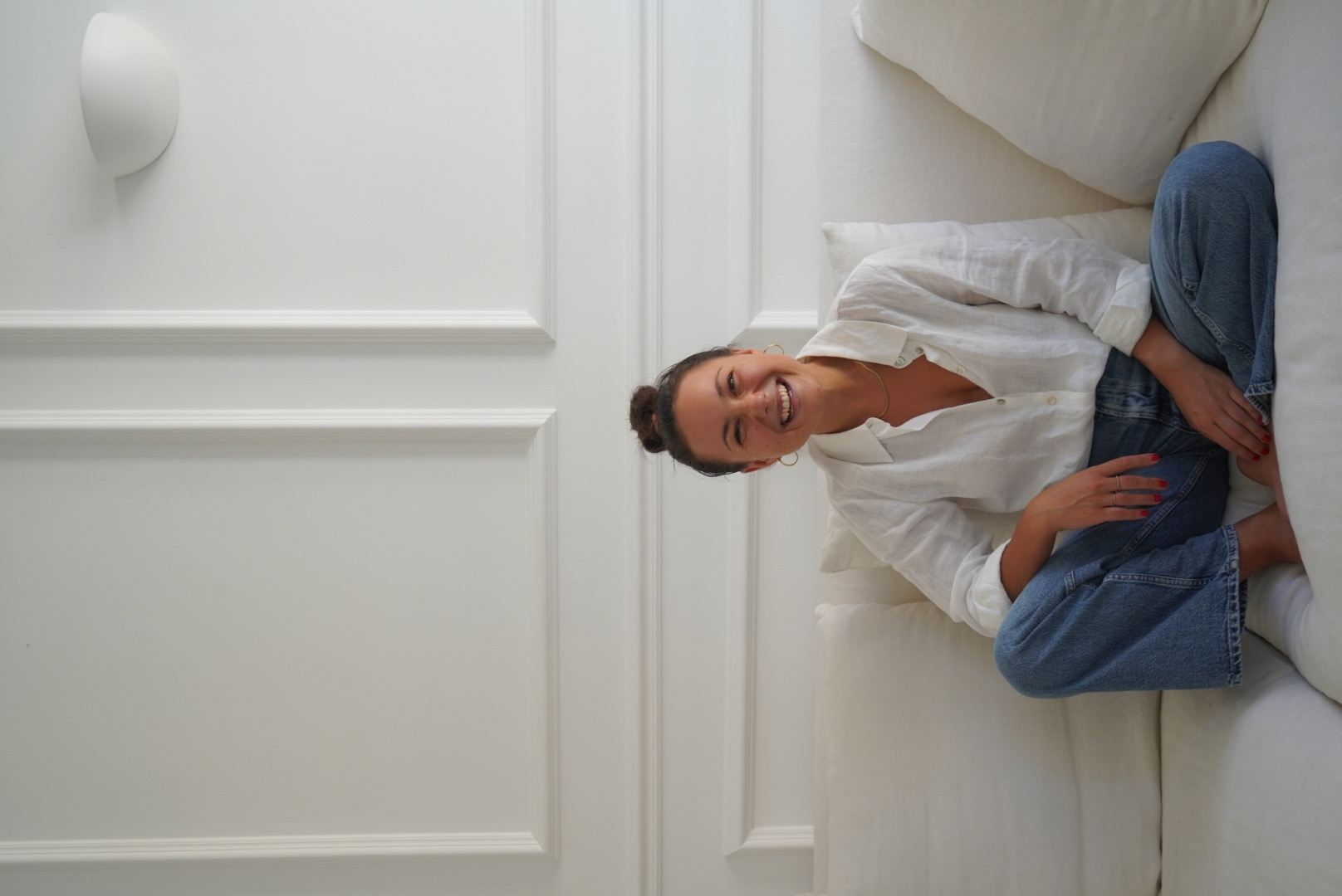 Marie, founder of the BaseLine app, relaxing on a white sofa