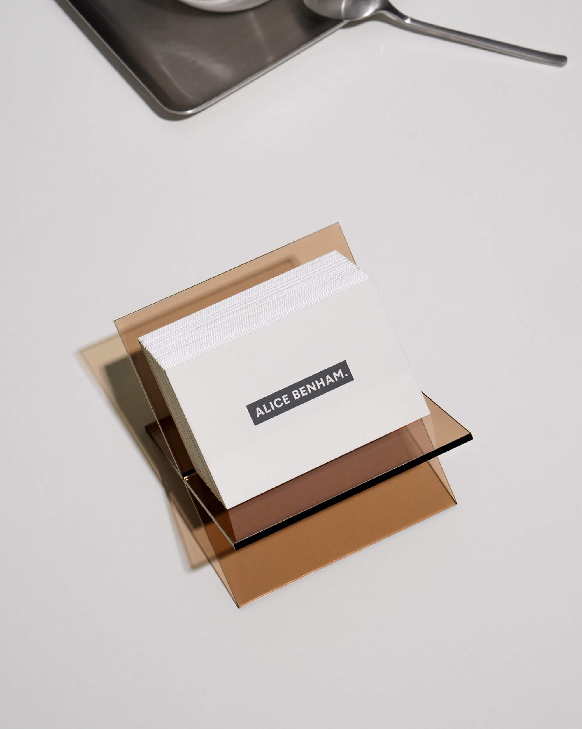 Alice Benham business cards stacked on amber acrylic, printed with her black wordmark label