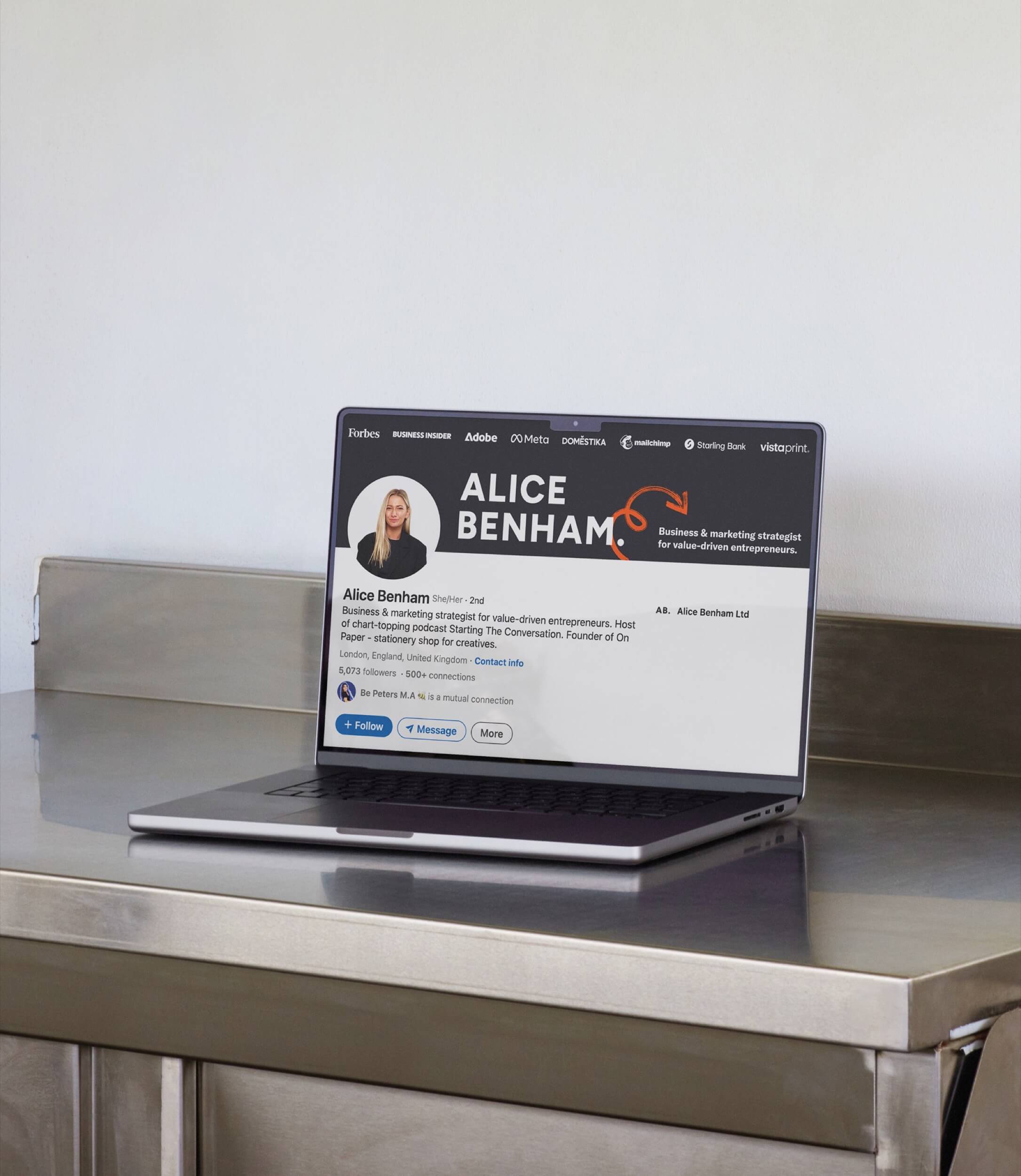 Alice Benham LinkedIn profile with her new banner and wordmark, shown on a laptop on a steel table