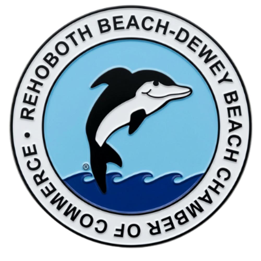 Circular logo with a black and white dolphin jumping over stylized blue waves on a light blue background, surrounded by a white ring with the text 'Rehoboth Beach-Dewey Beach Chamber of Commerce'.
