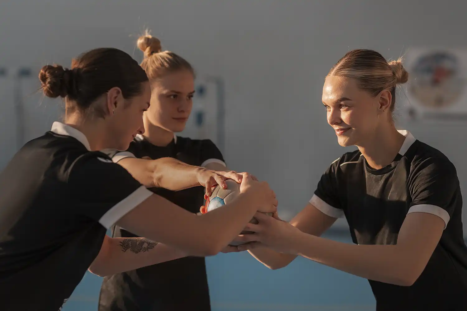 Trois handballeuses s’échangent une balle lors d’un exercice collectif en salle de sport