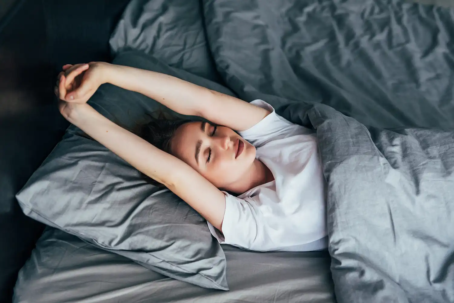 Personne étirée au lit après séance sport, récupération optimale pour performance musculaire