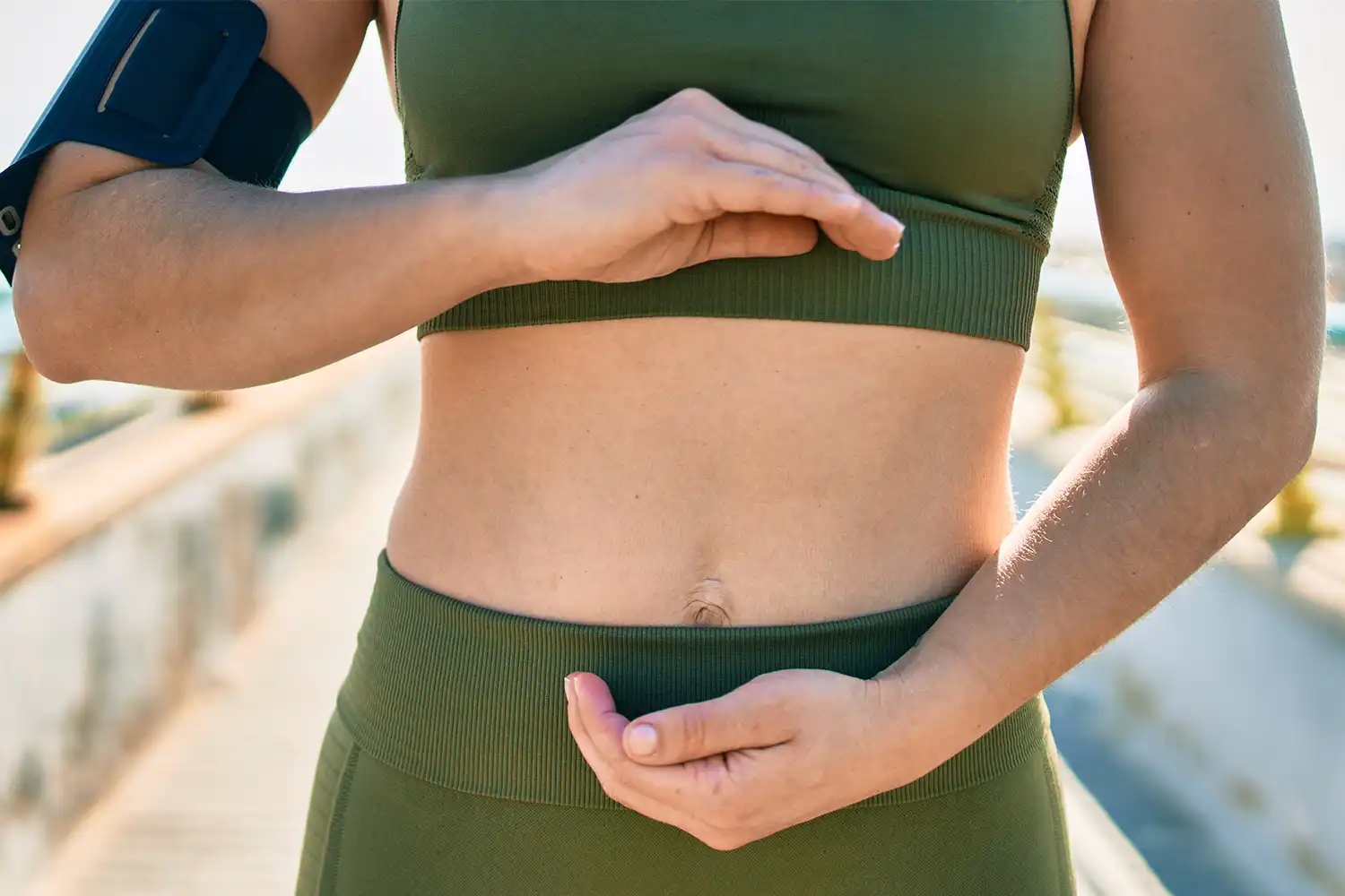 Personne ajustant brassière sport compression près d’un parcours extérieur fitness