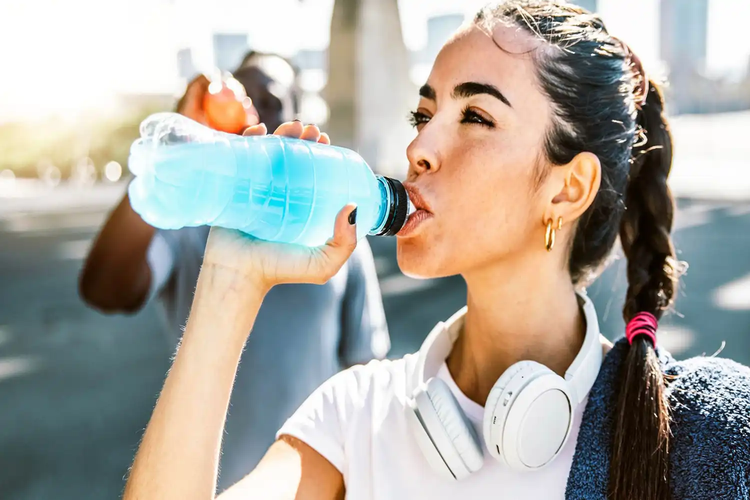 Sportive boit eau isotonique après séance fitness, équipée écouteurs