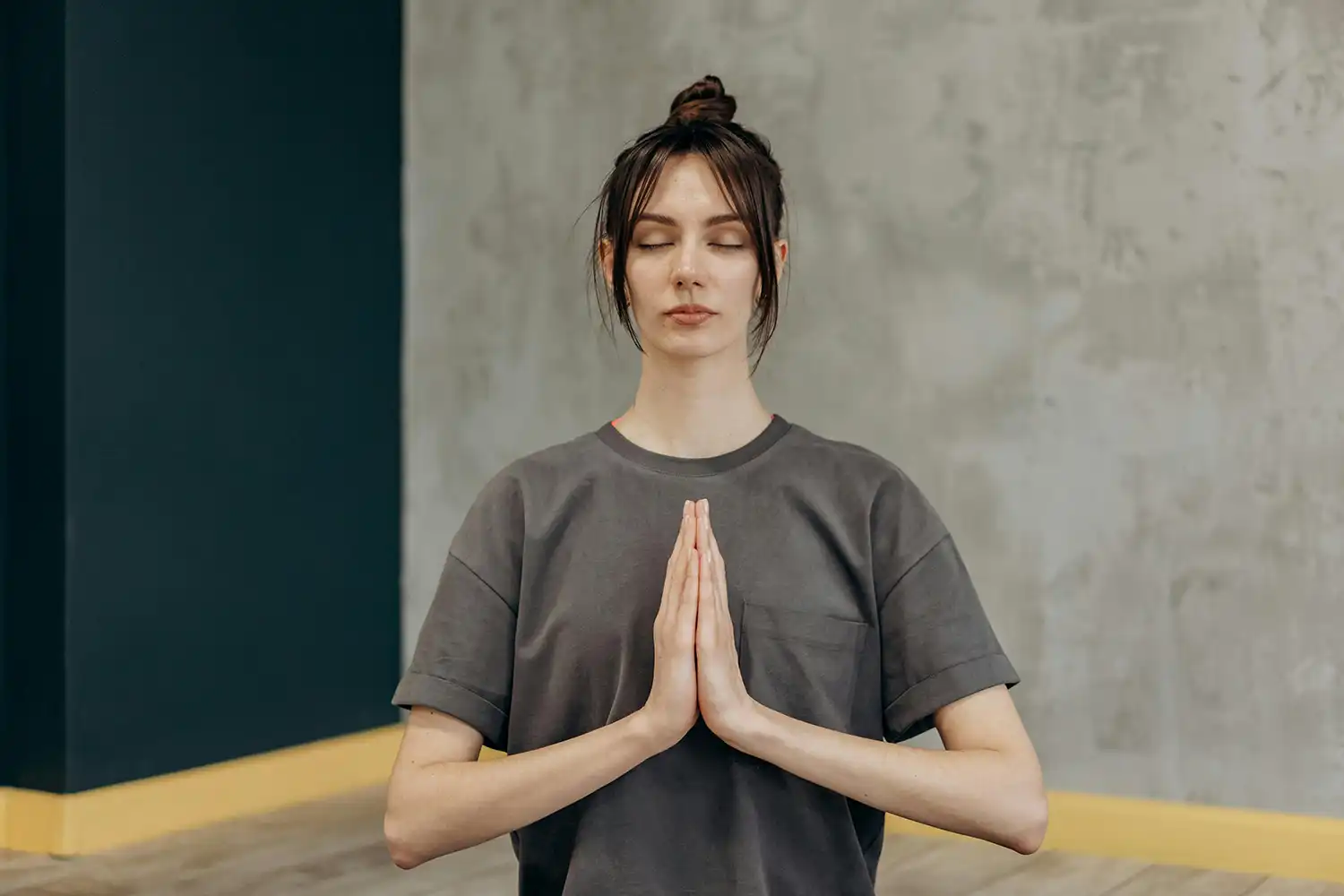 Femme en posture méditative mains jointes, pratique yoga respiration calme salle sport moderne