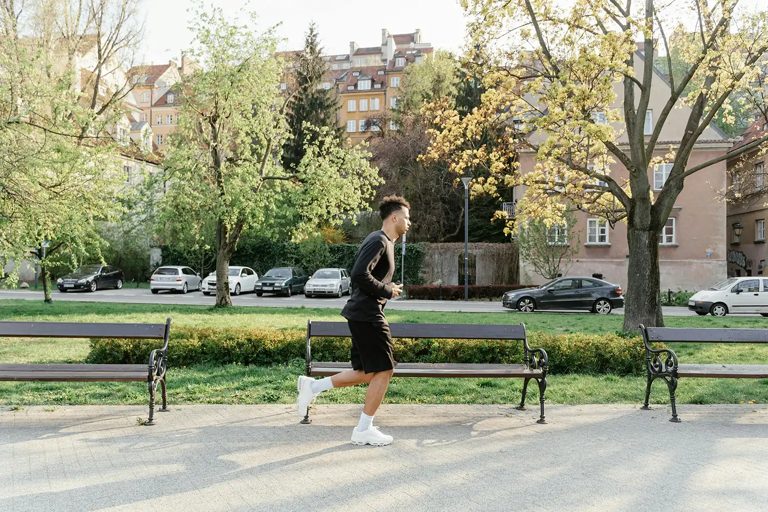 Personne faisant du sport en extérieur avec haltères près d’un parc, idéal pour s’entraîner au printemps.