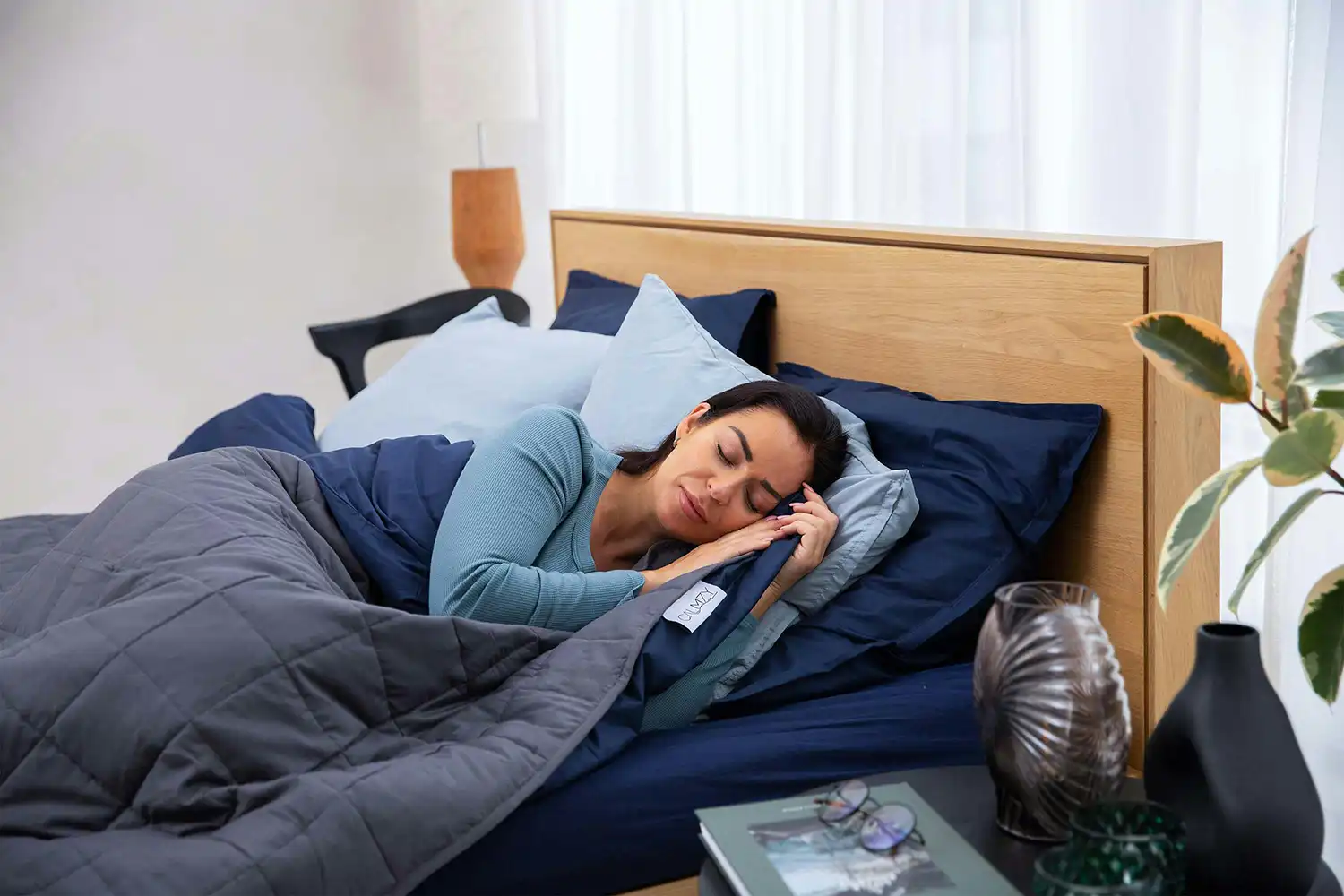 Femme détendue en position de sommeil sur lit avec couverture légère, idéale pour récupération post-effort