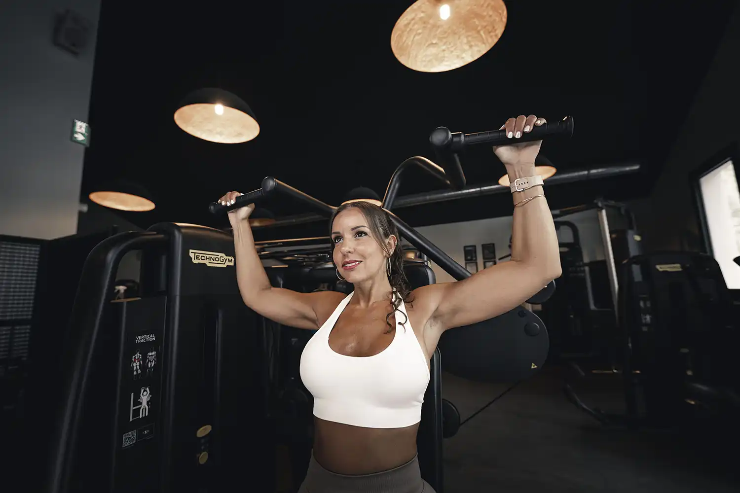 Femme en salle de sport utilisant barre de traction pour musculation dorsale et bras