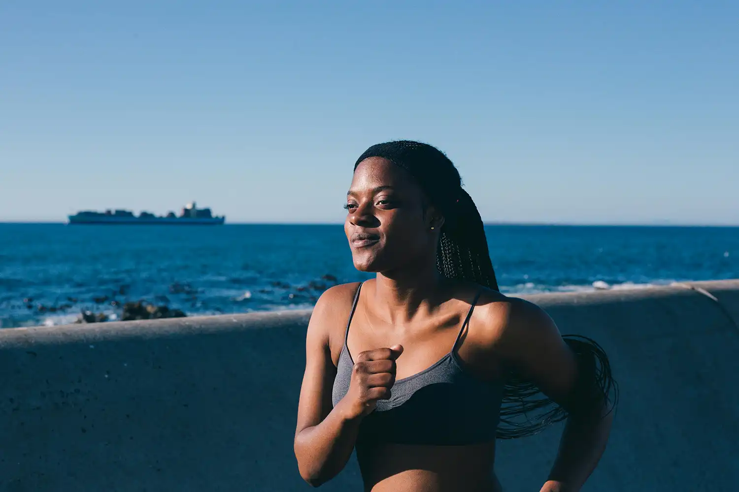 Femme souriant près de l’eau, tenue légère idéale pour activité sportive estivale.