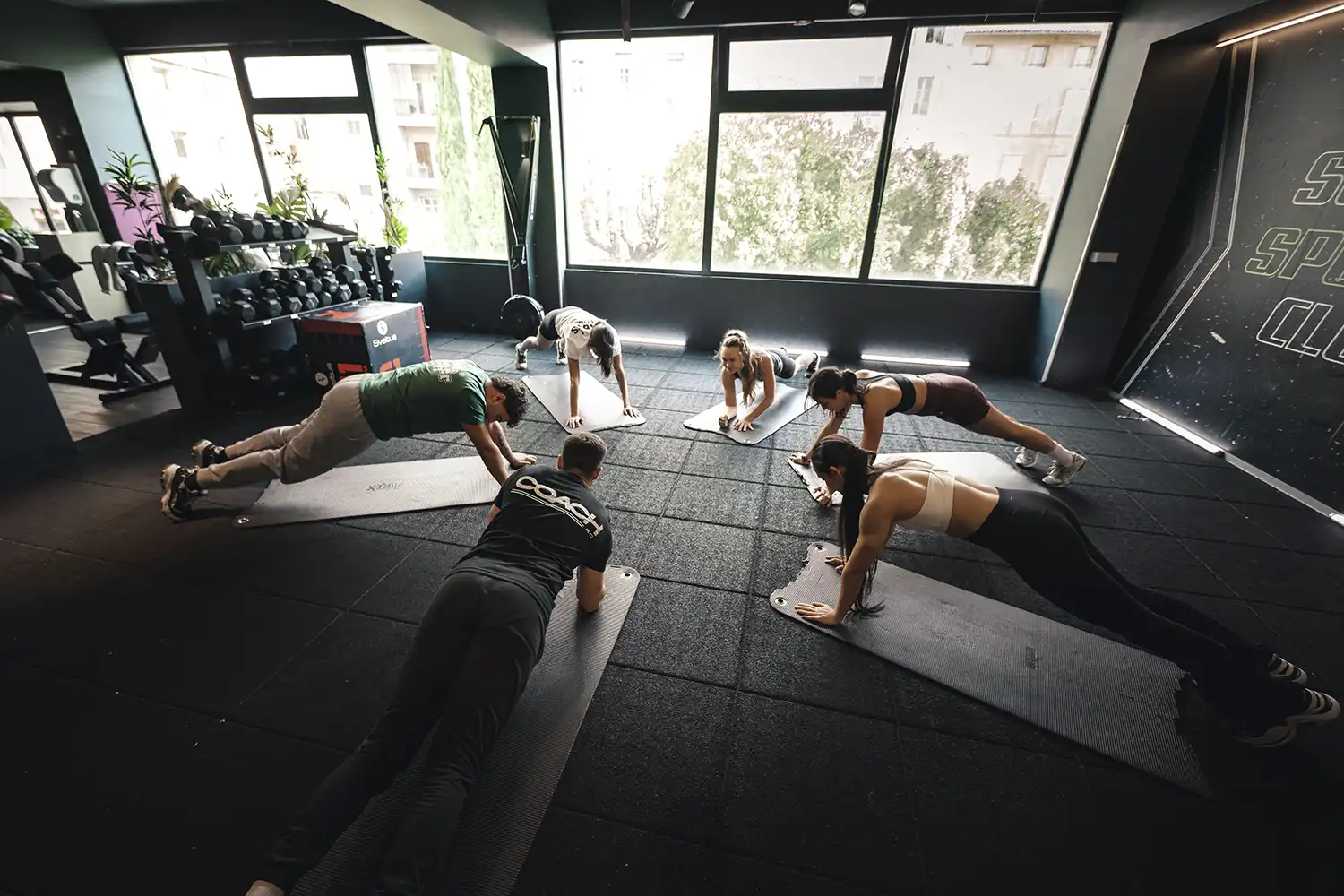 Exercices abdominaux en salle de sport, trois athlètes en position planche pour renforcement musculaire