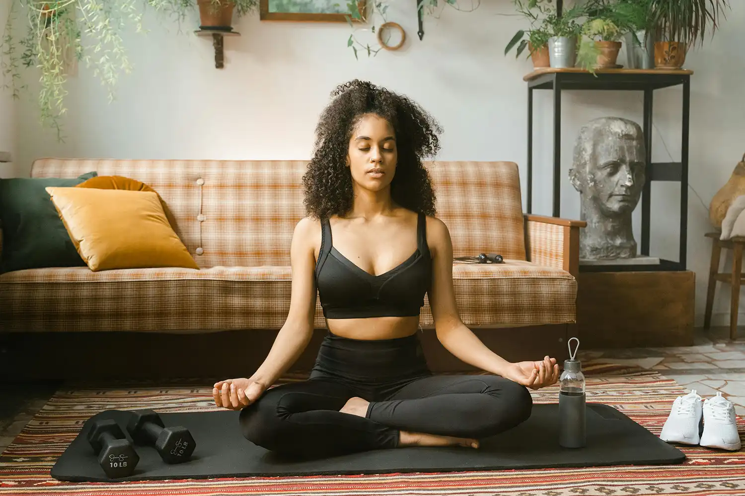 Femme en méditation sur tapis de yoga, posture assise, salle de sport home training.