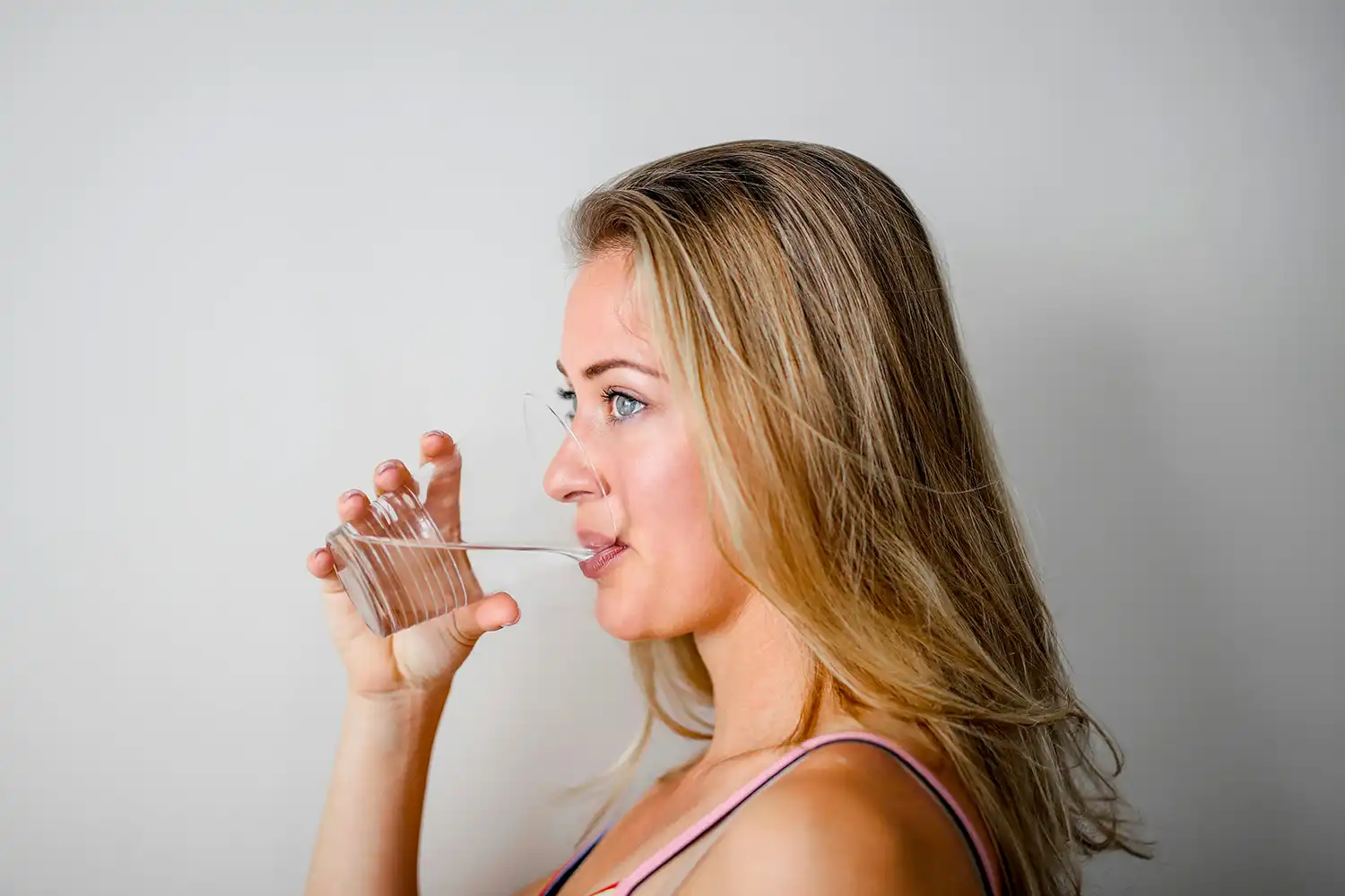 Hydratation femme boit eau avec paille salle sport