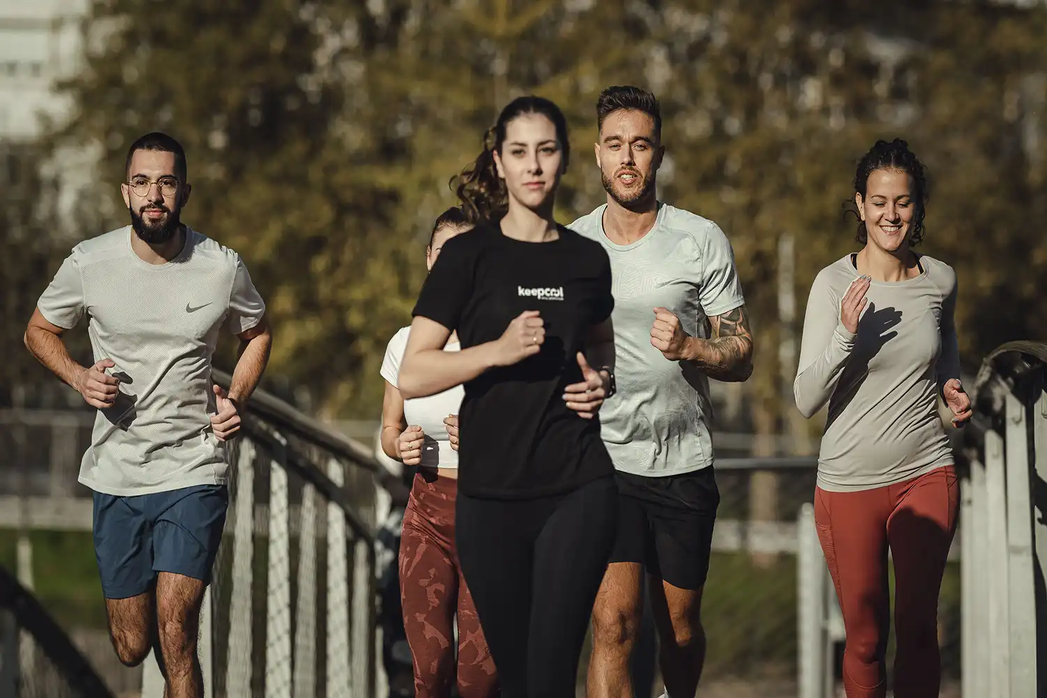 Quatre athlètes courant ensemble en extérieur, tenue sport moderne, activité fitness automne.