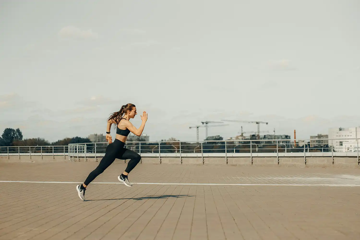 Athlète en mouvement sur tapis de course extérieur, séance cardio dynamique en extérieur.
