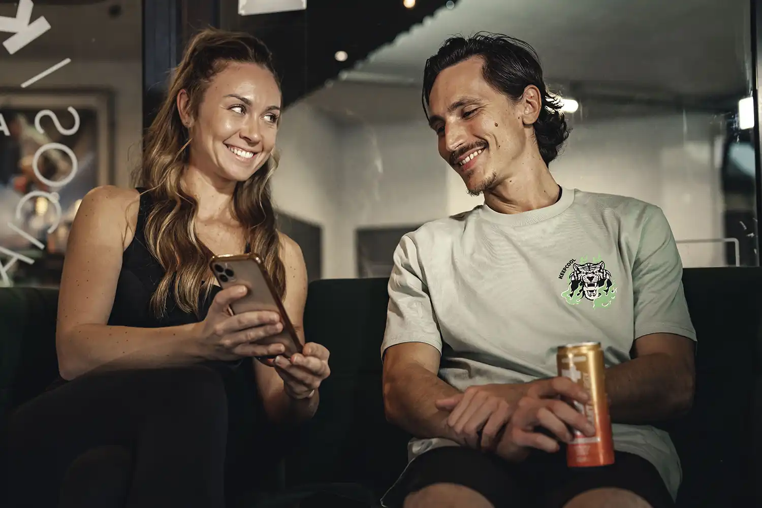Deux personnes souriantes détendent avec boissons dans salle de sport Keepcool.