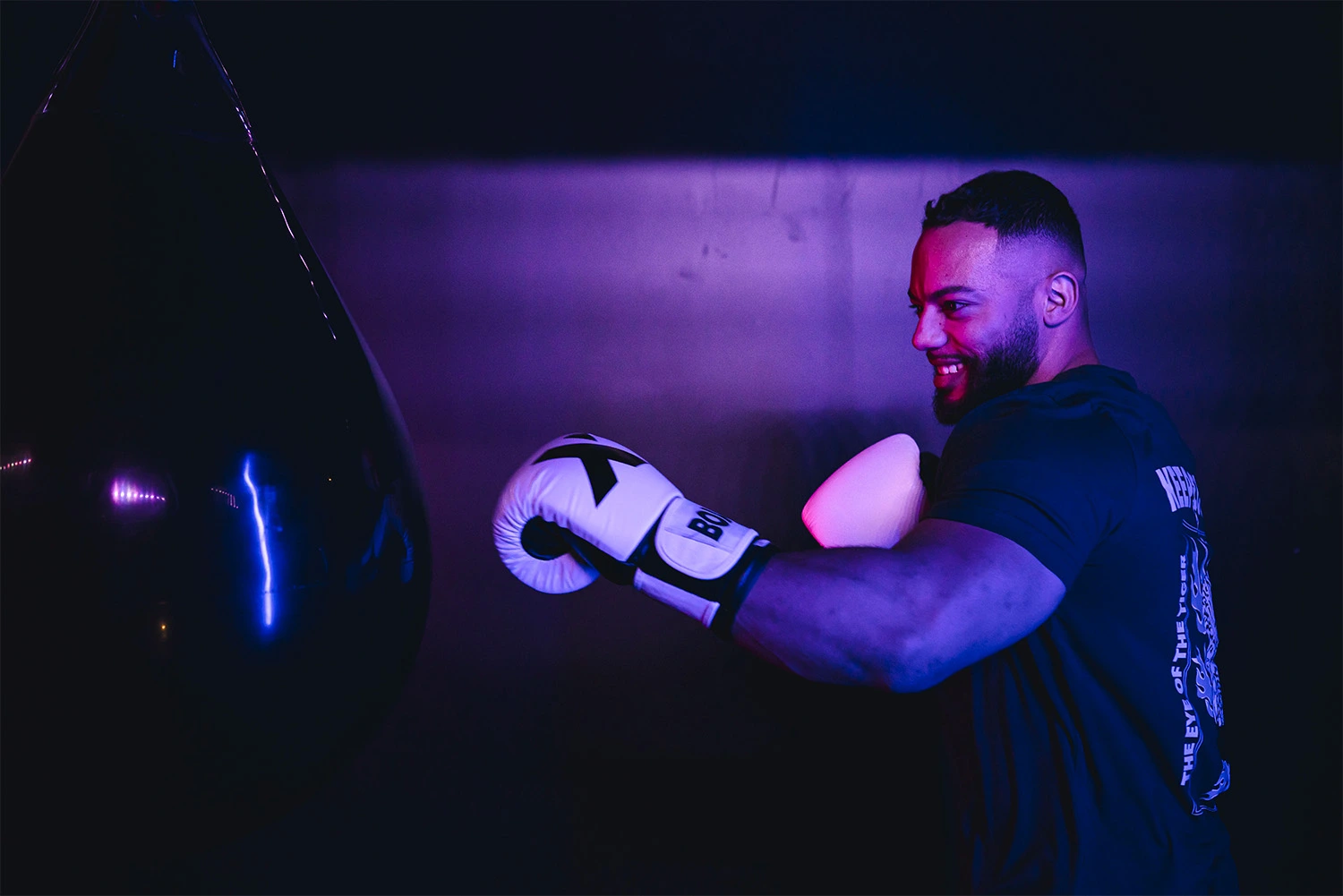 Homme en salle de sport frappant sac de boxe avec gants Keepcool