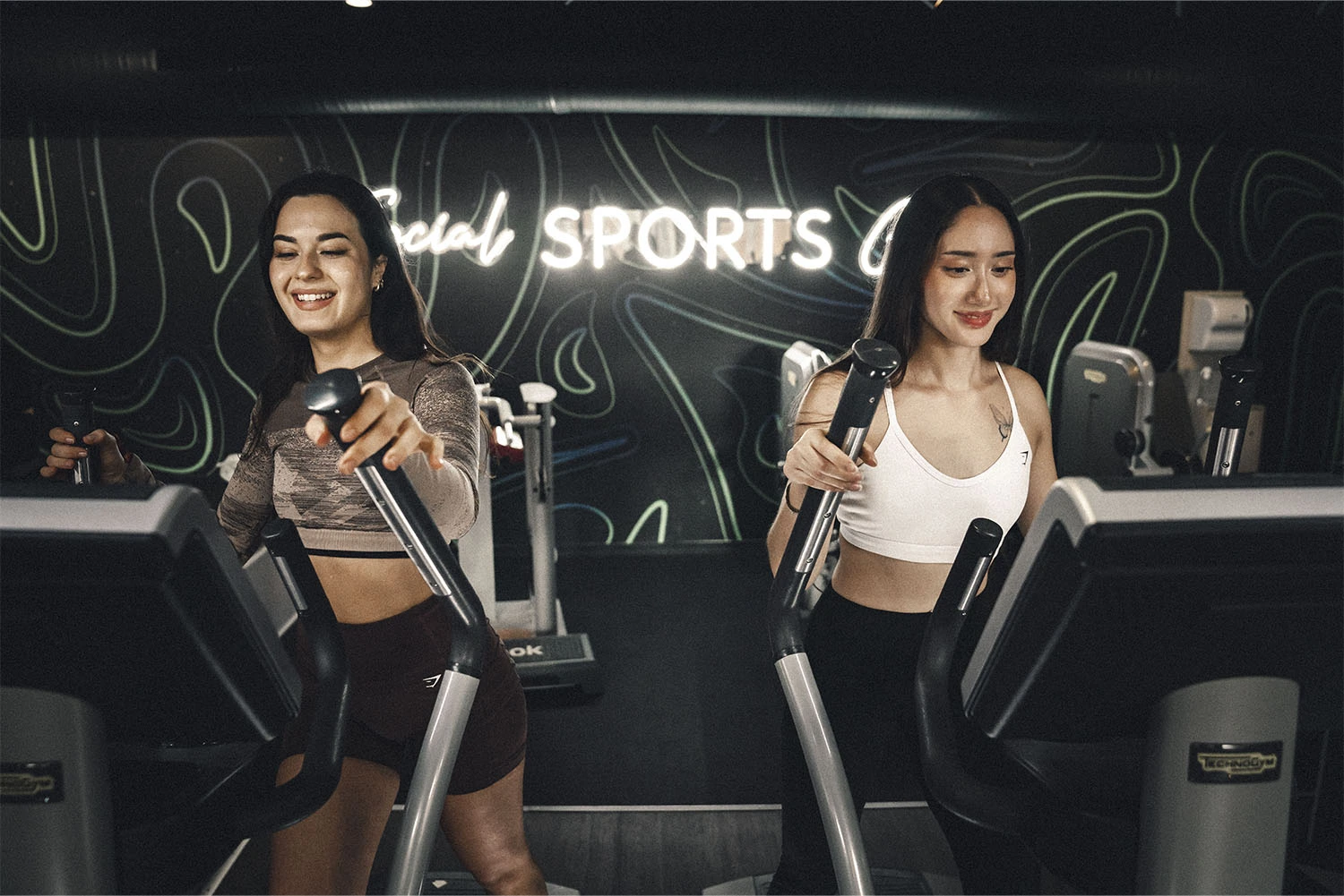 Deux femmes utilisant des appareils elliptiques en salle de sport Keepcool pour séance cardio.