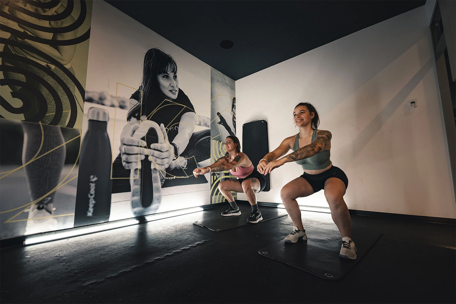Deux athlètes en salle de sport réalisant un exercice de renforcement musculaire avec haltères, ambiance motivante Keepcool.